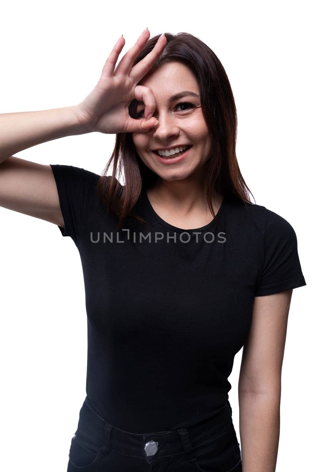 Young European woman dressed in a black T-shirt smiling on a white background with copy space by TRMK