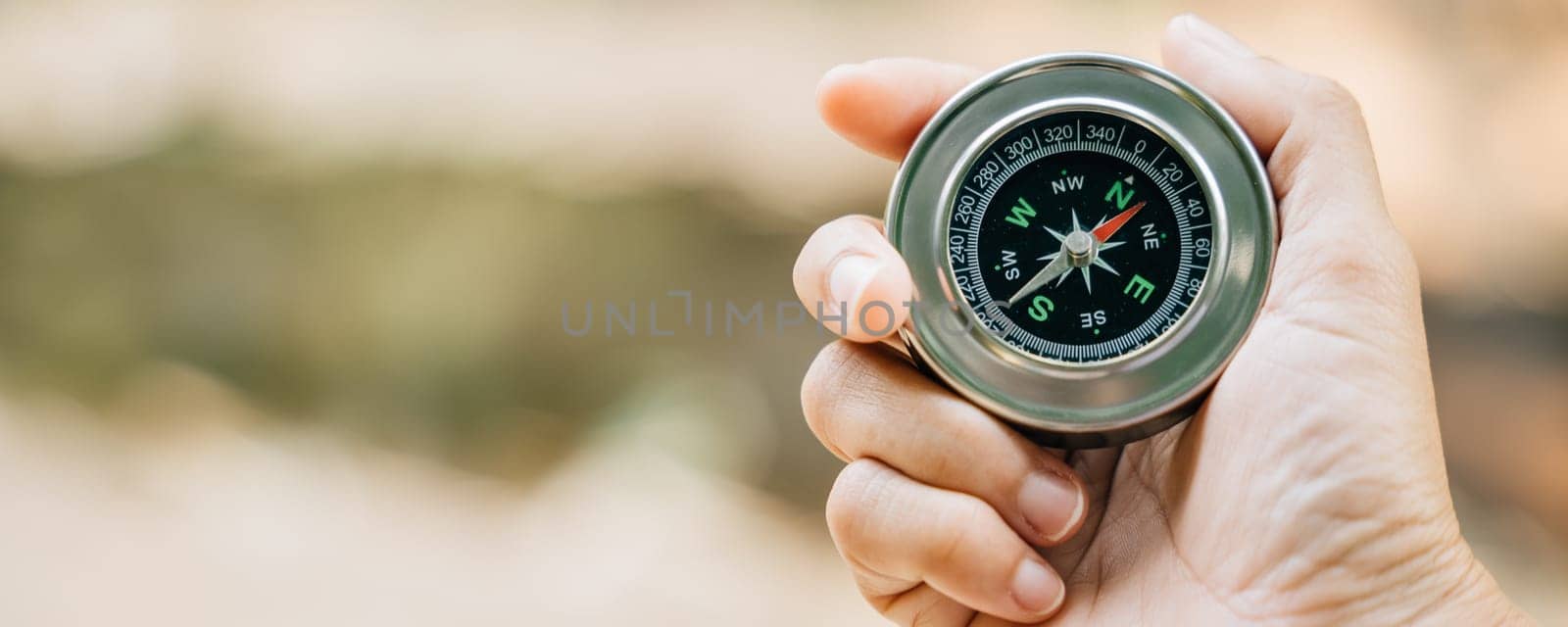 Traveler holds a compass in park seeking guidance amidst the beauty of nature. The compass in her hand symbolizes exploration and her journey to find direction in the forest captivating surroundings.
