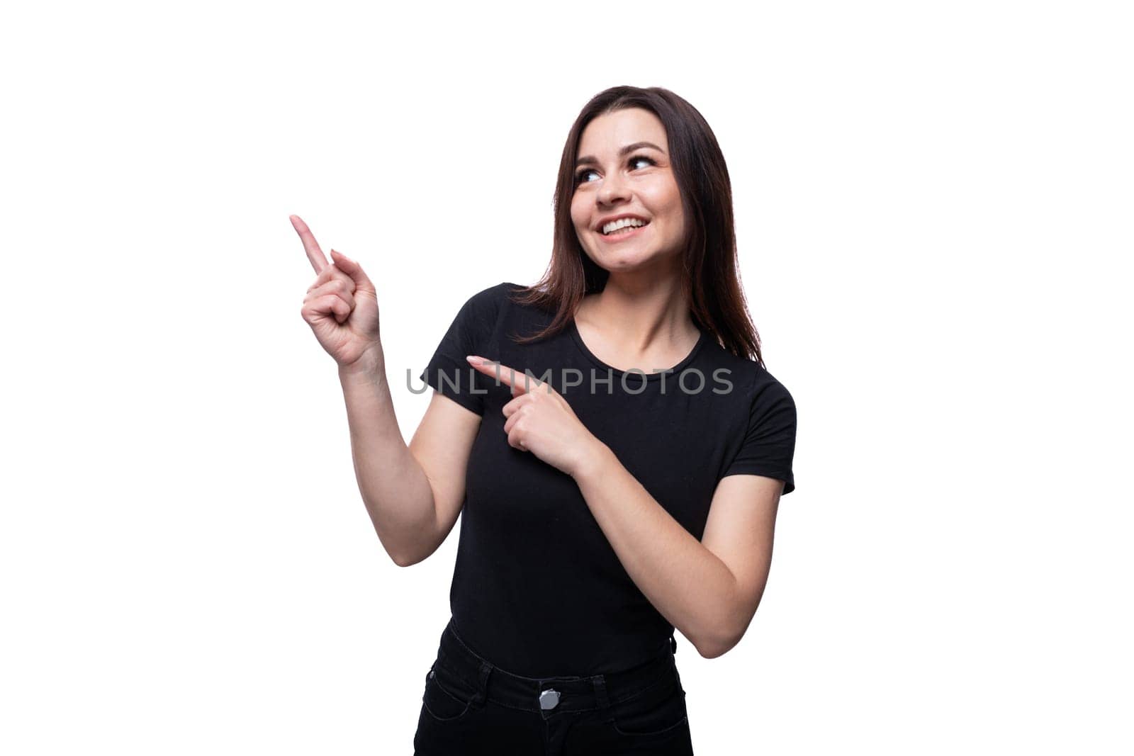 Young Caucasian woman with brown eyes dressed in black clothes looks to the side and points with her finger.