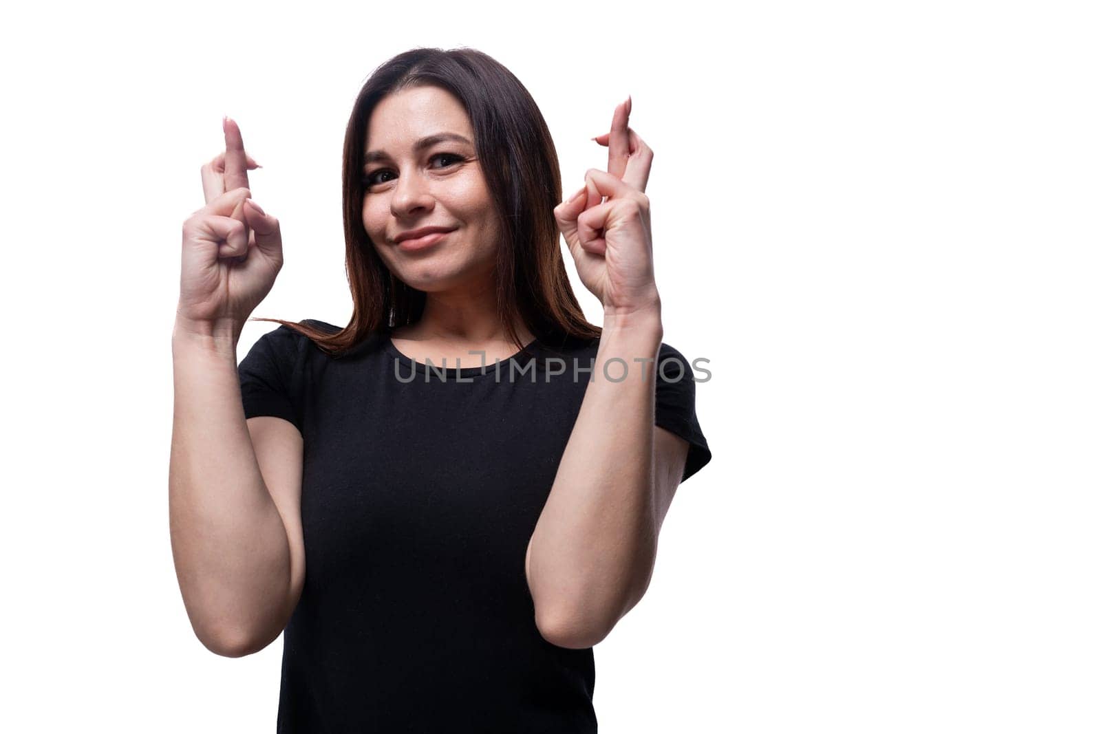 Young European woman dressed in a black T-shirt crossing her fingers.