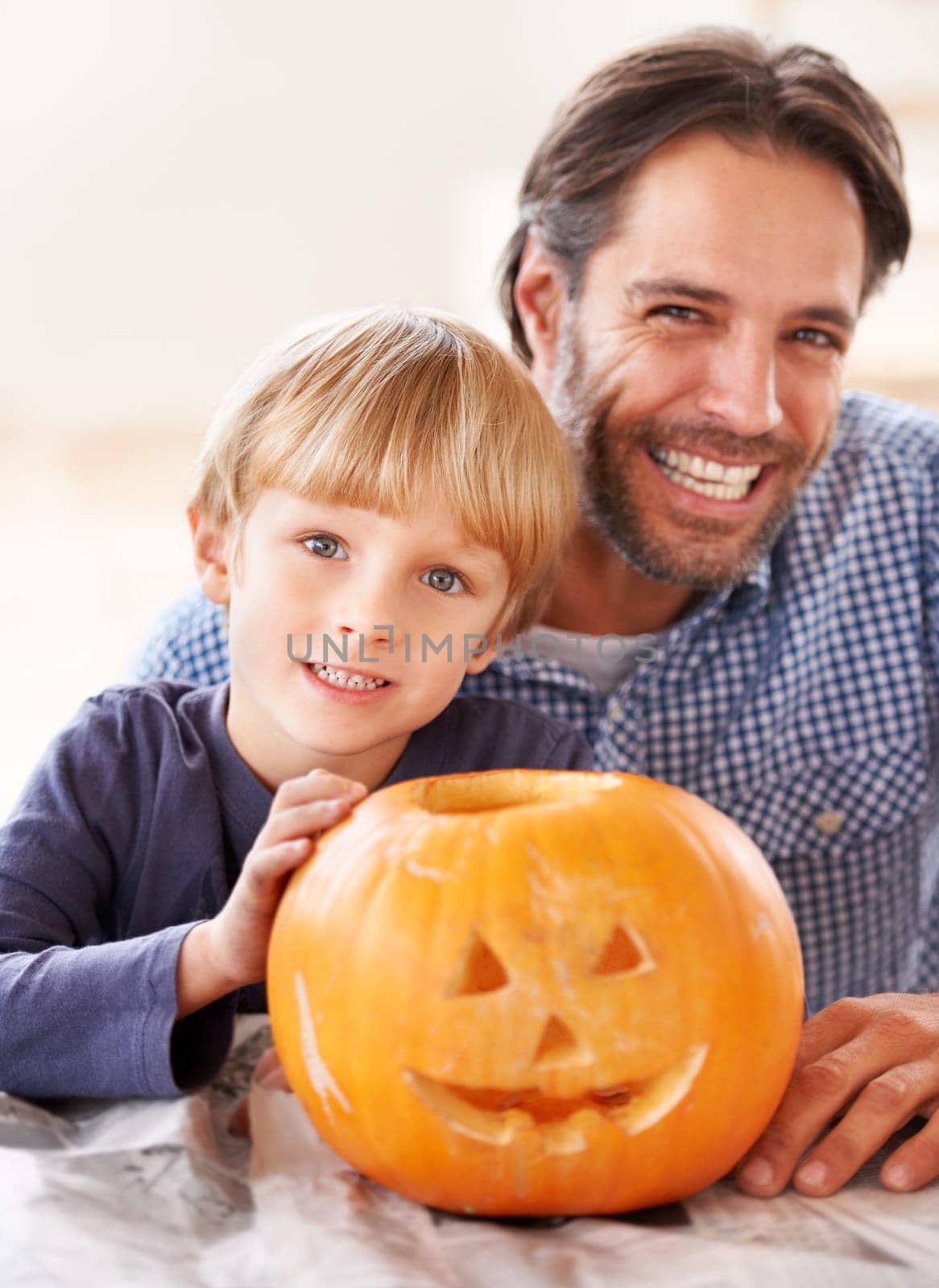 Proud of their jack-o-lantern. Portrait of a father and son behind their carved pumpkin for halloween