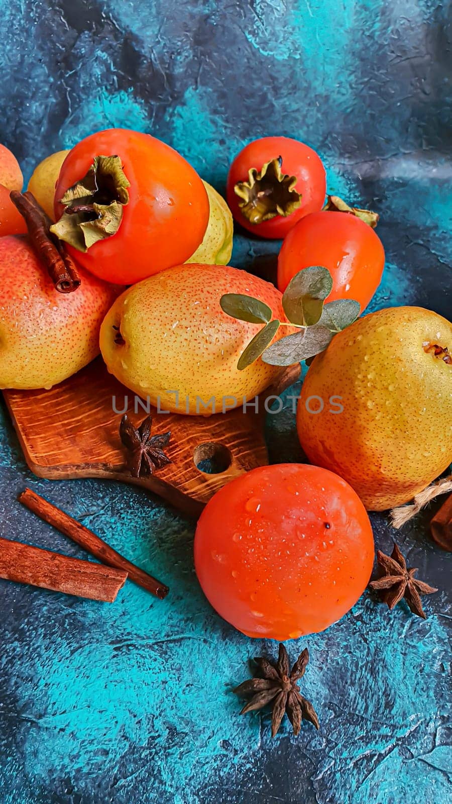 Persimmon on a dark background. Fresh, ripe fruits on a blue plate and in a box. Healthy eating.