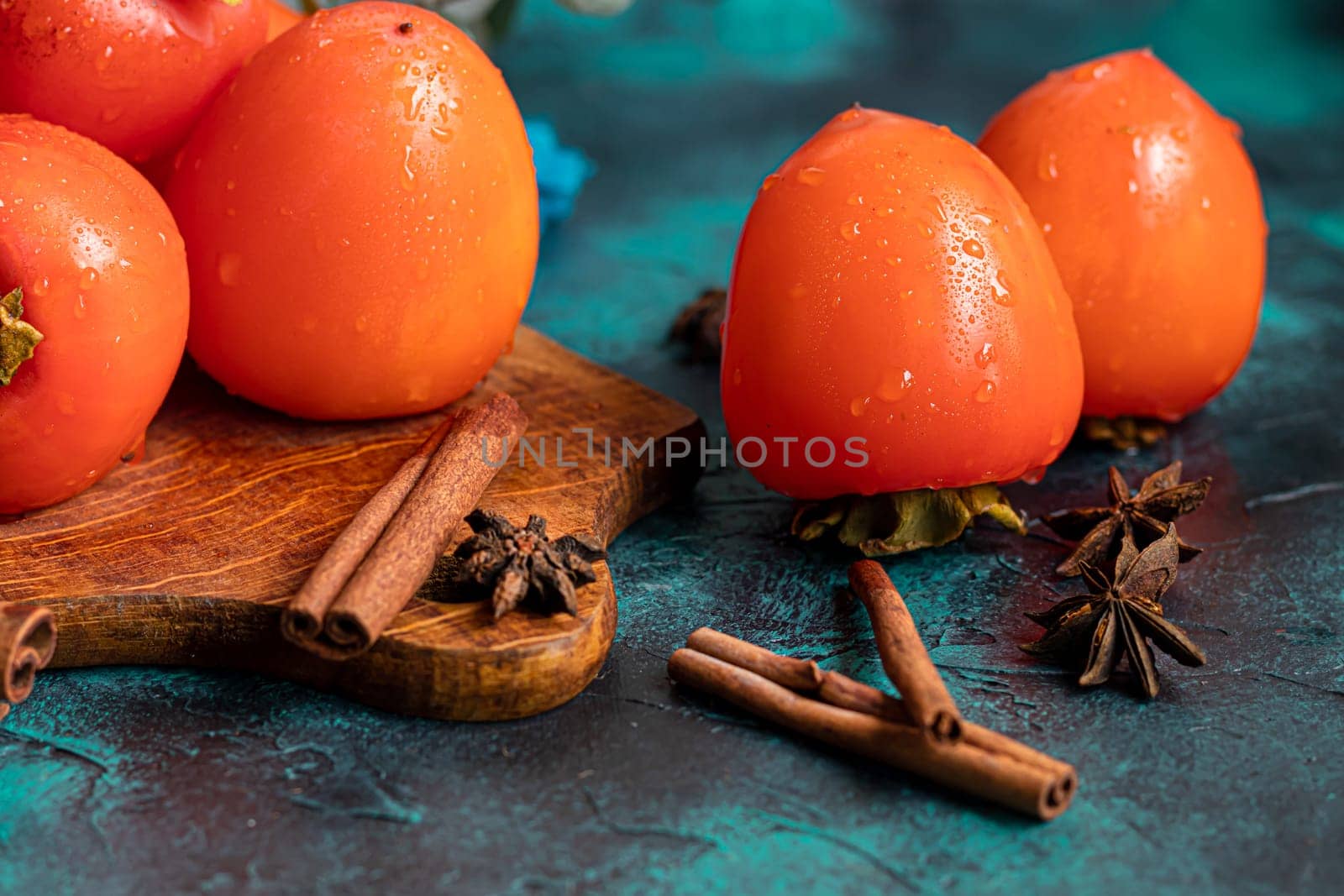 Persimmon on a dark background. Fresh, ripe fruits on a blue plate and in a box. Healthy eating.