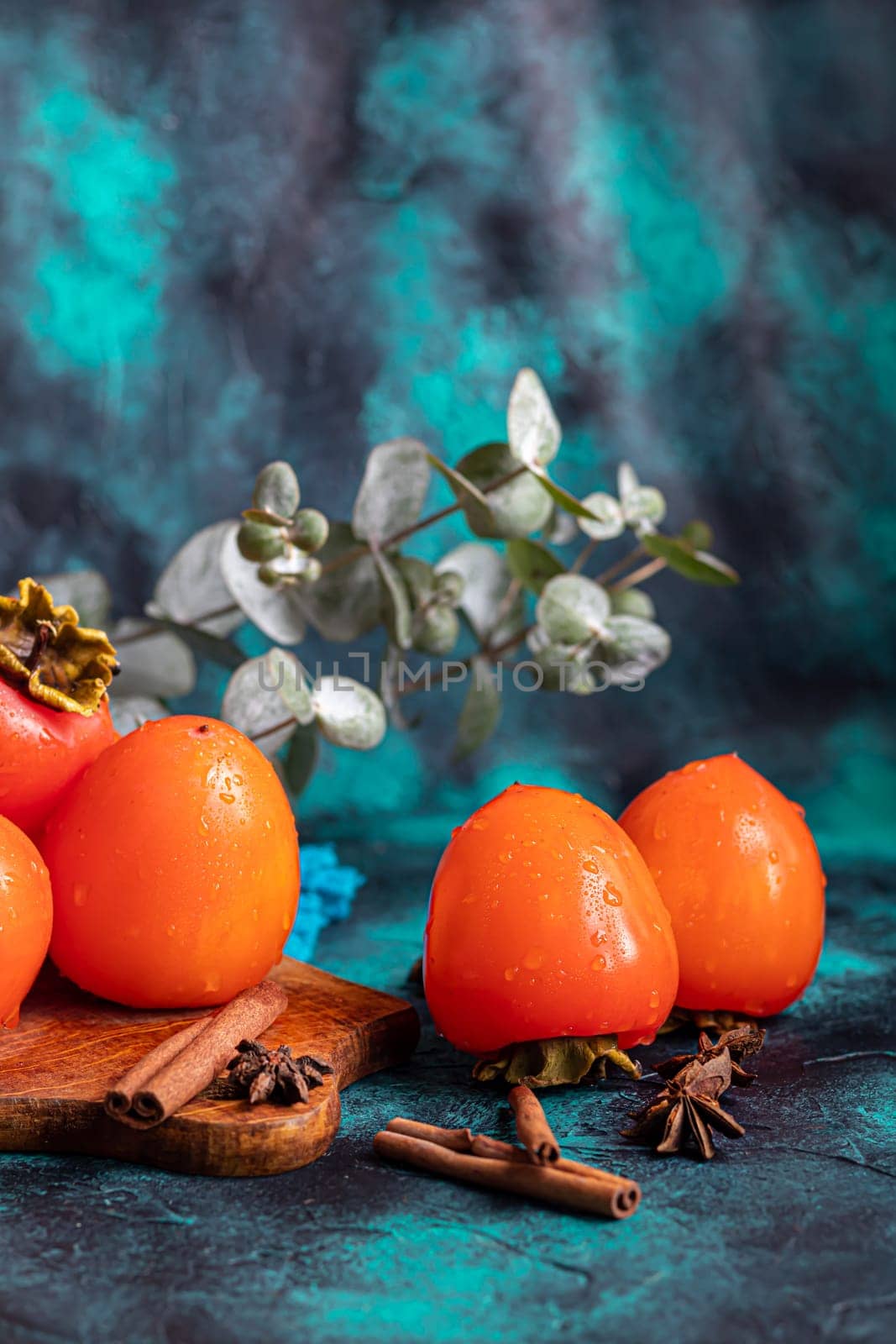 Persimmon on a dark background. Fresh, ripe fruits on a blue plate and in a box. Healthy eating.