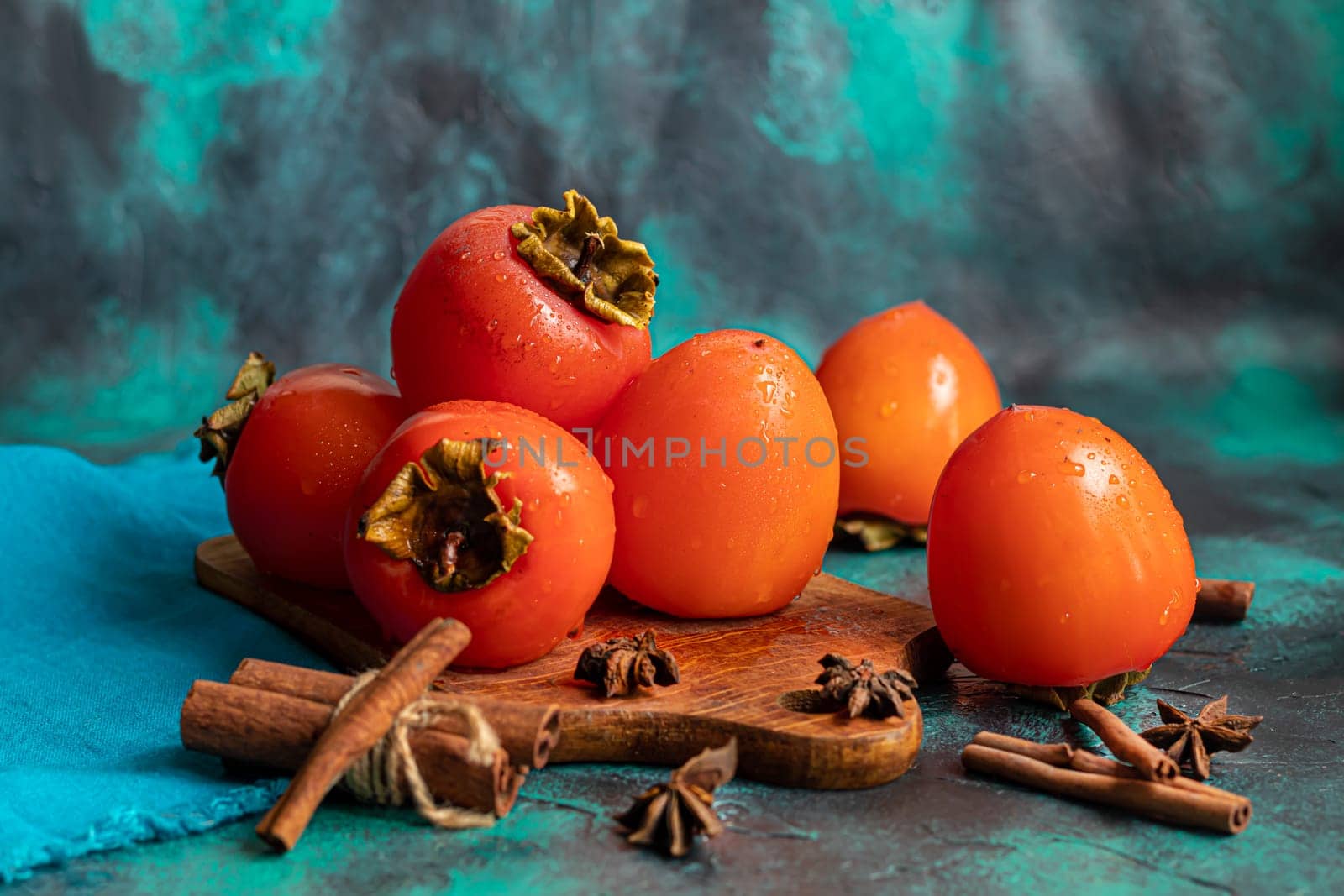 Persimmon on a dark background. Fresh, ripe fruits on a blue plate and in a box. Healthy eating.