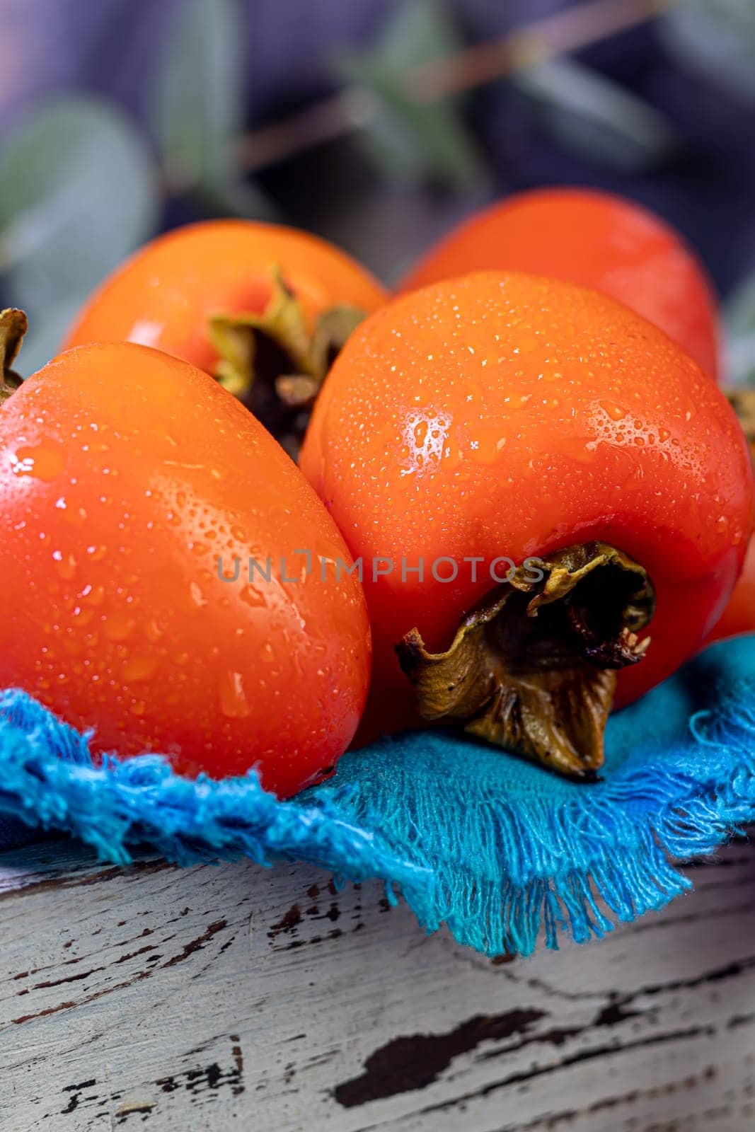 Persimmon on a dark background. Fresh, ripe fruits on a blue plate and in a box. Healthy eating.