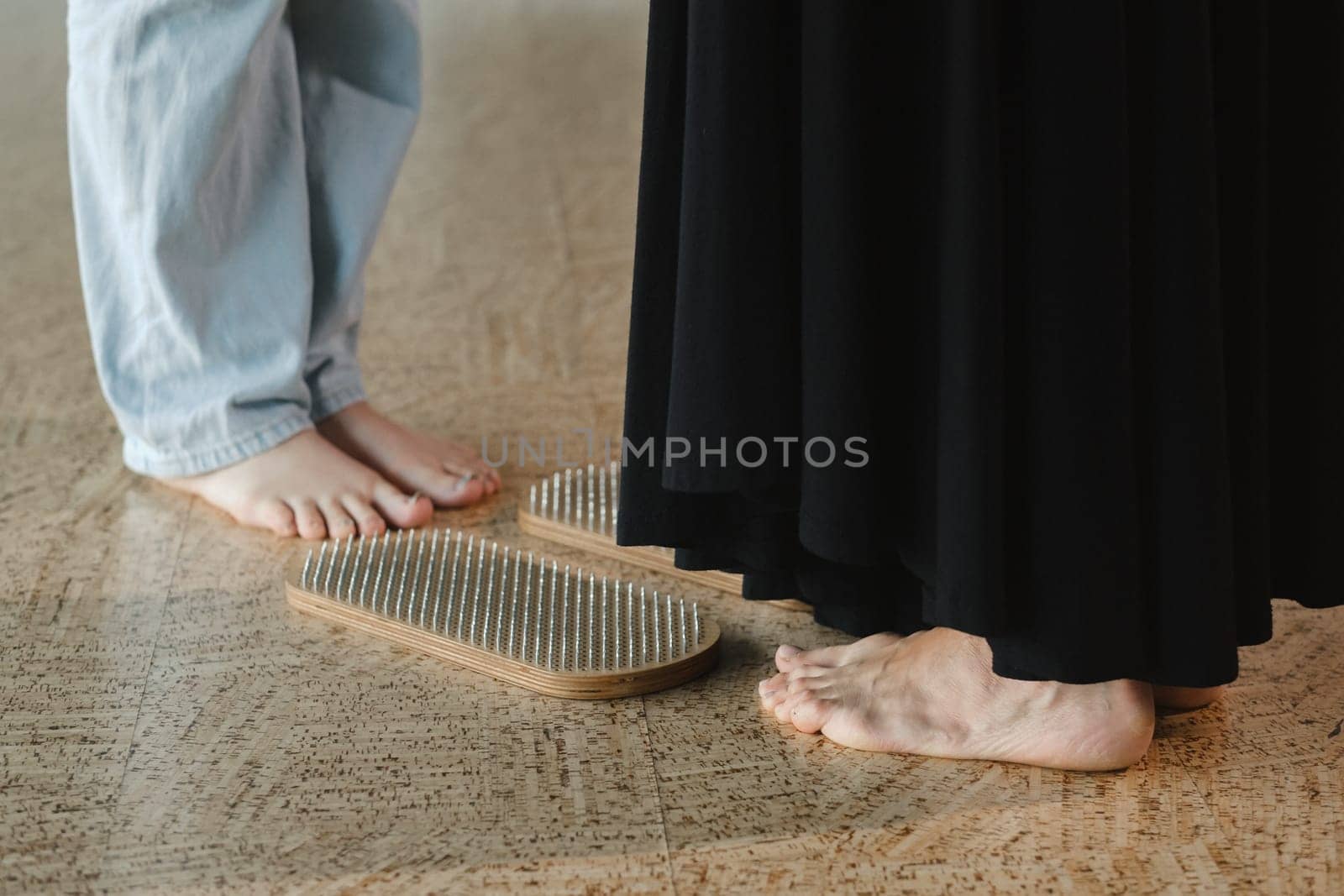 close-up of the legs of girls engaged in standing on a board with nails barefoot by Lobachad
