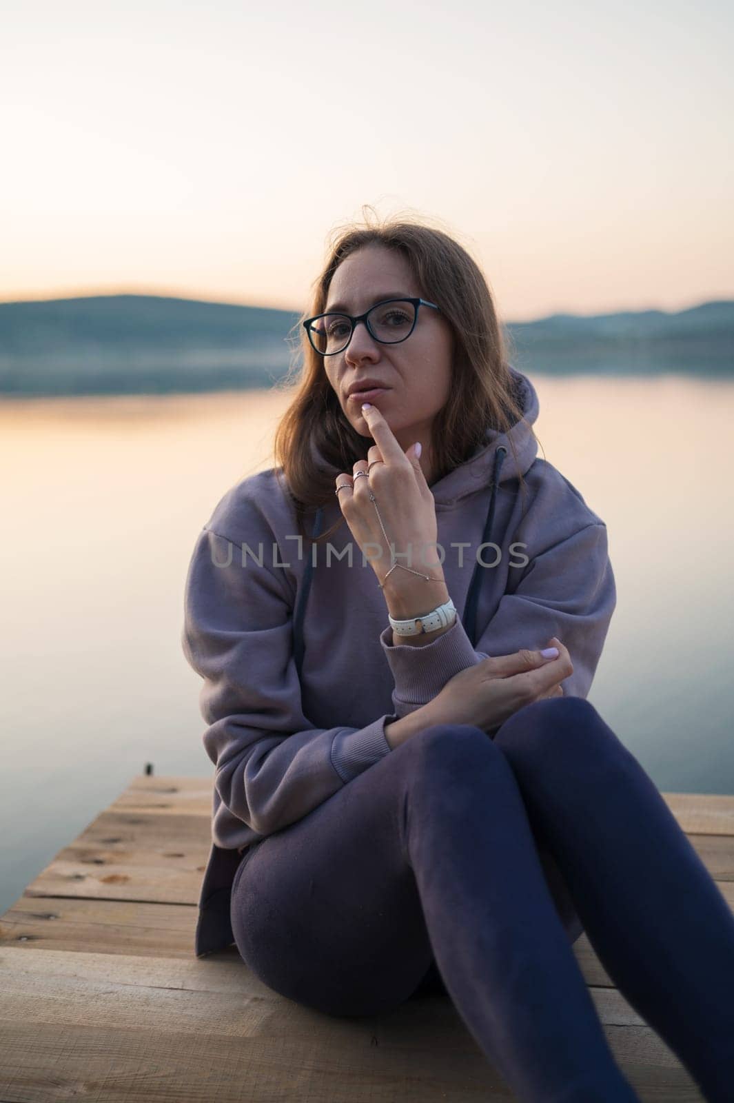 Woman sitting on the pier, closeup portrait, summer sunset