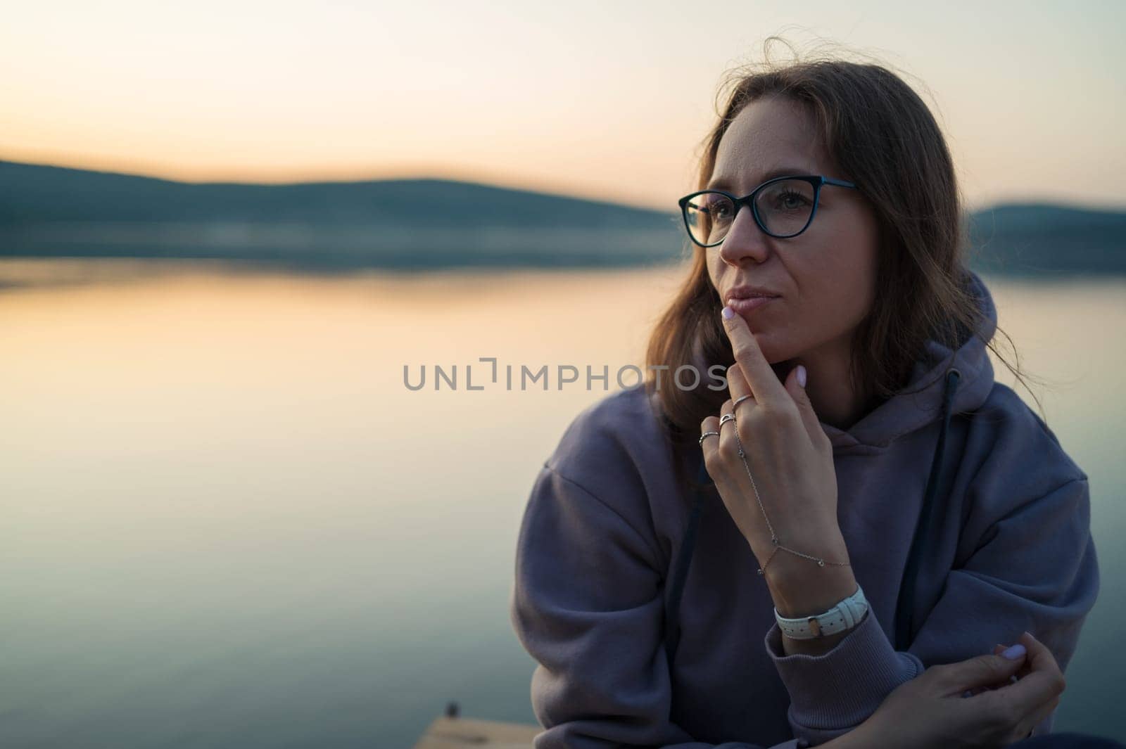 Woman sitting on the pier, closeup portrait, summer sunset