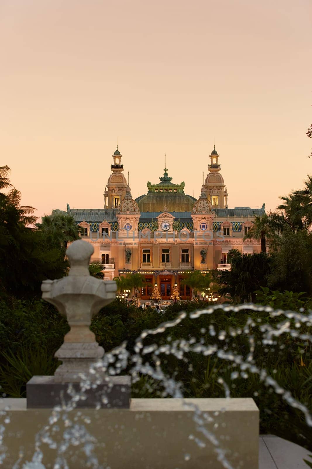 Monaco, Monte-Carlo, 12 November 2022: The famous square of Casino Monte-Carlo is at dusk, attraction night illumination, luxury cars, players, tourists, splashes of fountain. High quality photo