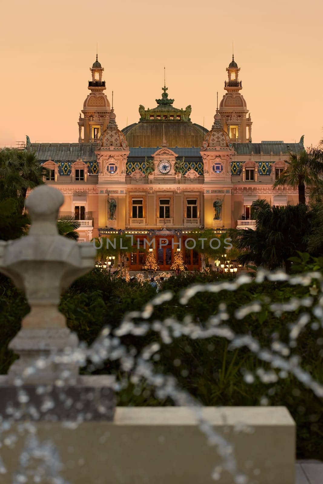 Monaco, Monte-Carlo, 12 November 2022: The famous square of Casino Monte-Carlo is at dusk, attraction night illumination, luxury cars, players, tourists, splashes of fountain. High quality photo