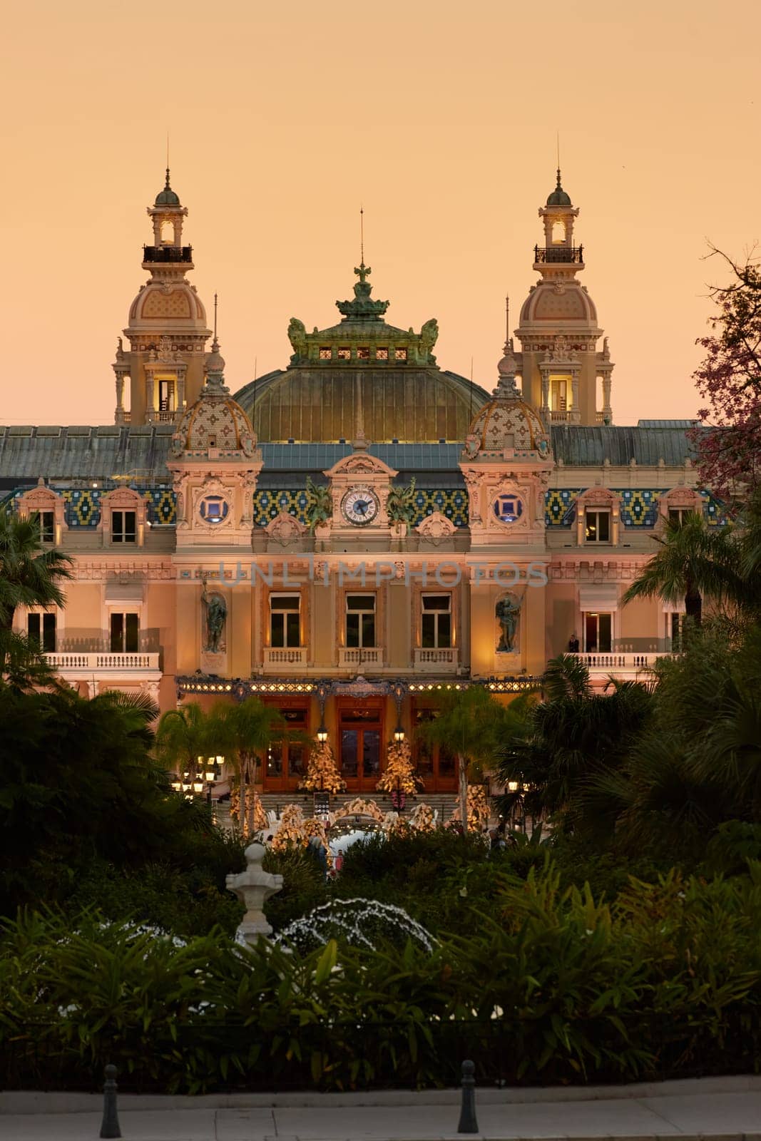 Monaco, Monte-Carlo, 12 November 2022: The famous square of Casino Monte-Carlo is at dusk, attraction night illumination, luxury cars, players, tourists, splashes of fountain. High quality photo