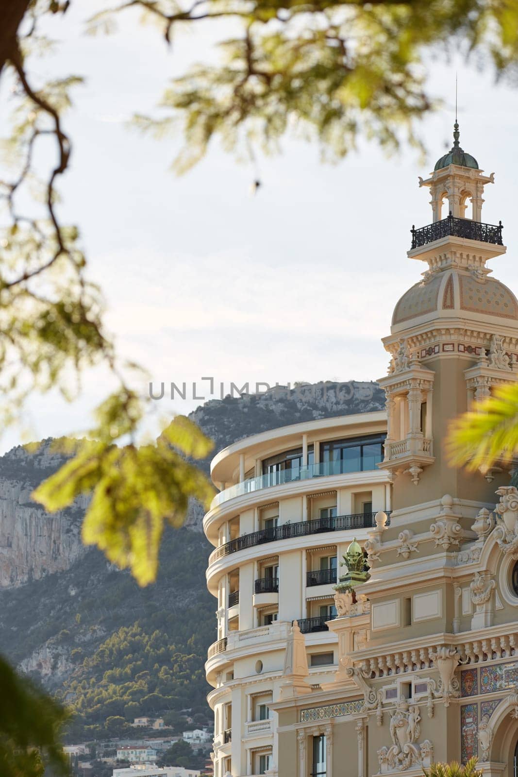 Monaco, Monte-Carlo, 21 October 2022: Towers of Casino Monte-Carlo at sunset, the famous hotel de Paris and mountain are on background, wealth life, famous landmark, pine trees, blue sky. High quality photo