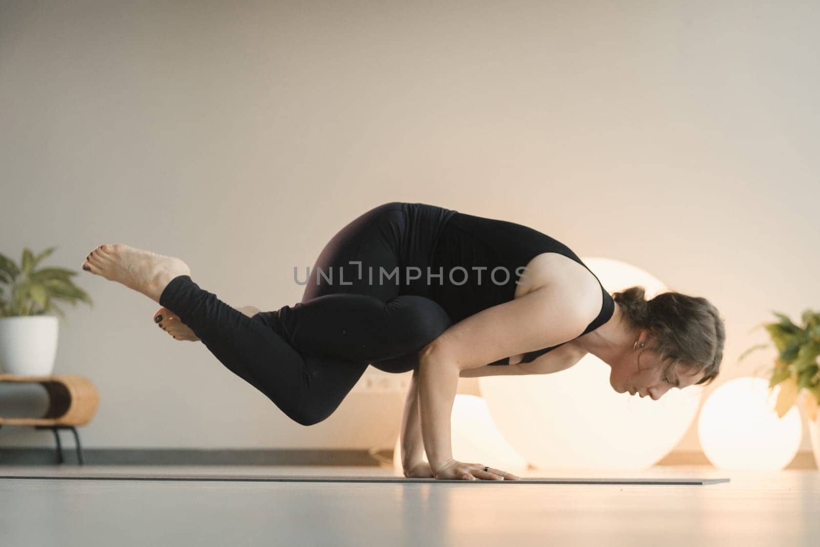 A girl in black sportswear does yoga on a mat in the fitness room.