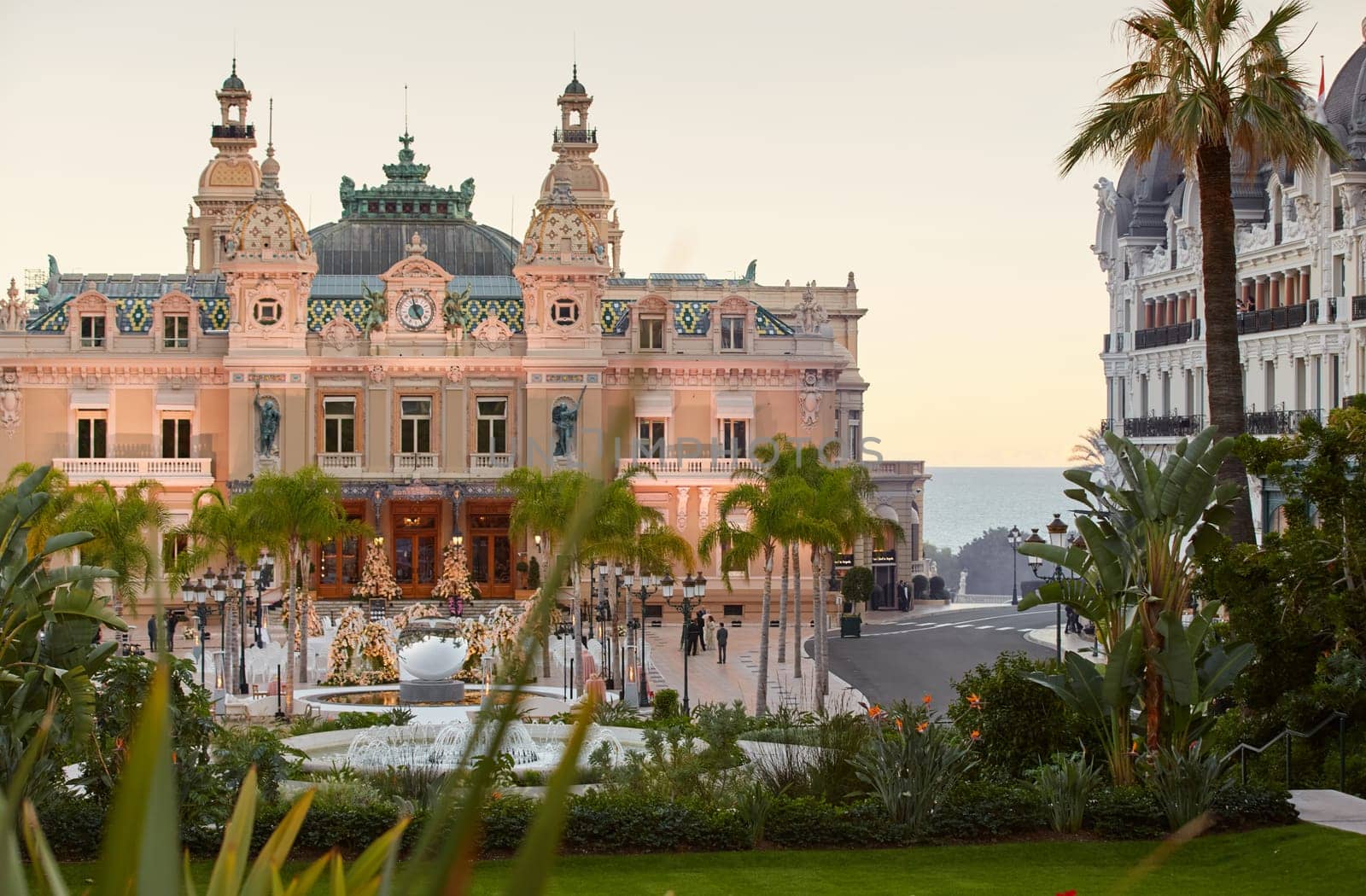 Monaco, Monte-Carlo, 12 November 2022: The famous square of Casino Monte-Carlo is at dusk, attraction night illumination, luxury cars, players, tourists, splashes of fountain. High quality photo