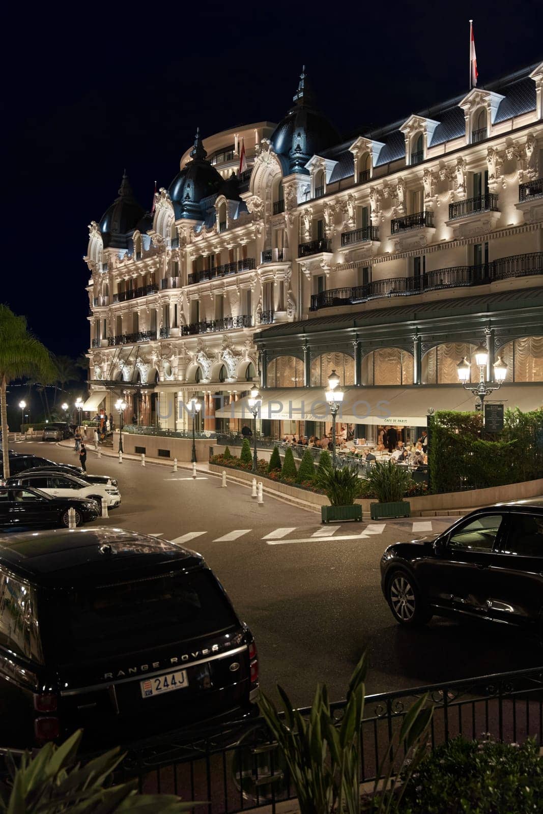 Monaco, Monte-Carlo, 12 November 2022: The famous square of Casino Monte-Carlo is at dusk, attraction night illumination, luxury cars, players, tourists, splashes of fountain. High quality photo