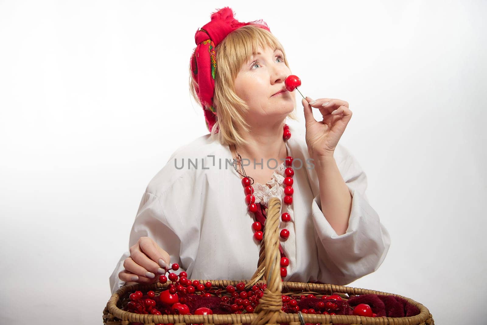Portrait of heerful funny adult mature woman solokha with red berries. Female model in national ethnic Slavic style. Stylized Ukrainian, Belarusian or Russian woman in comic photo shoot
