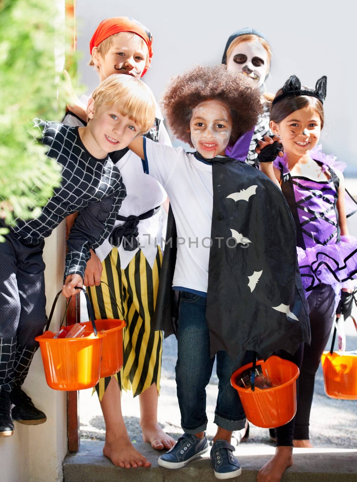 Our pales are full of candy. Portrait of a group of little children trick-or-treating on halloween. by YuriArcurs