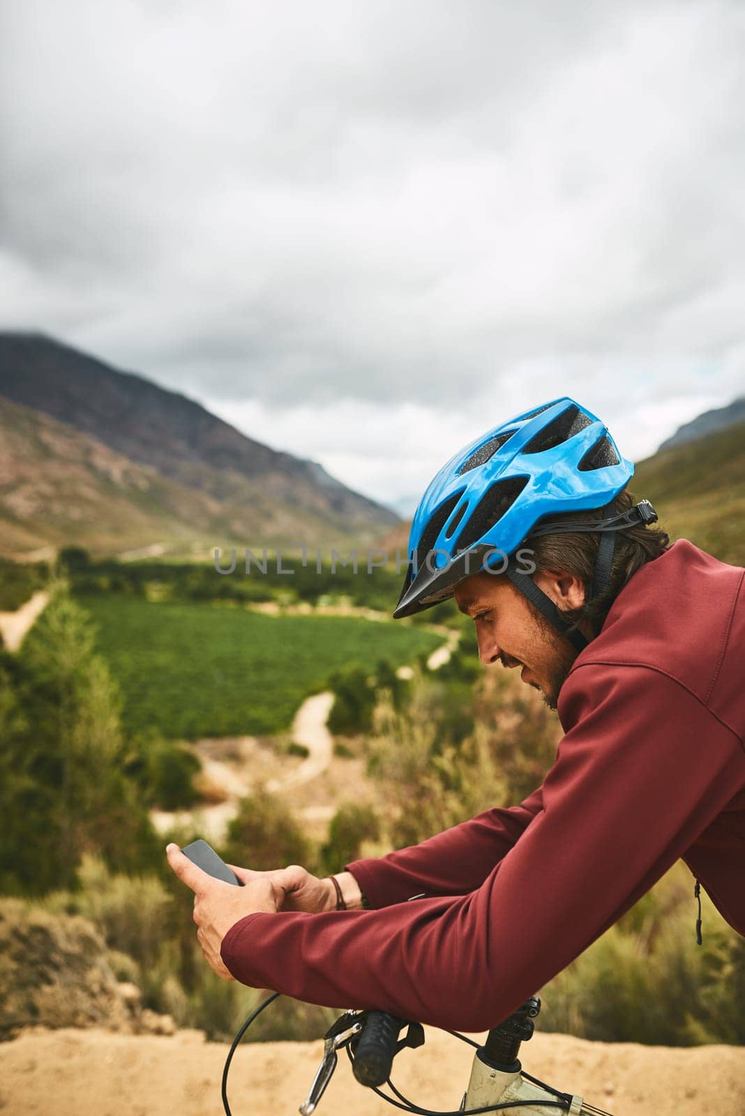 Technology takes him places. a young man using his cellphone while cycling along a trail. by YuriArcurs