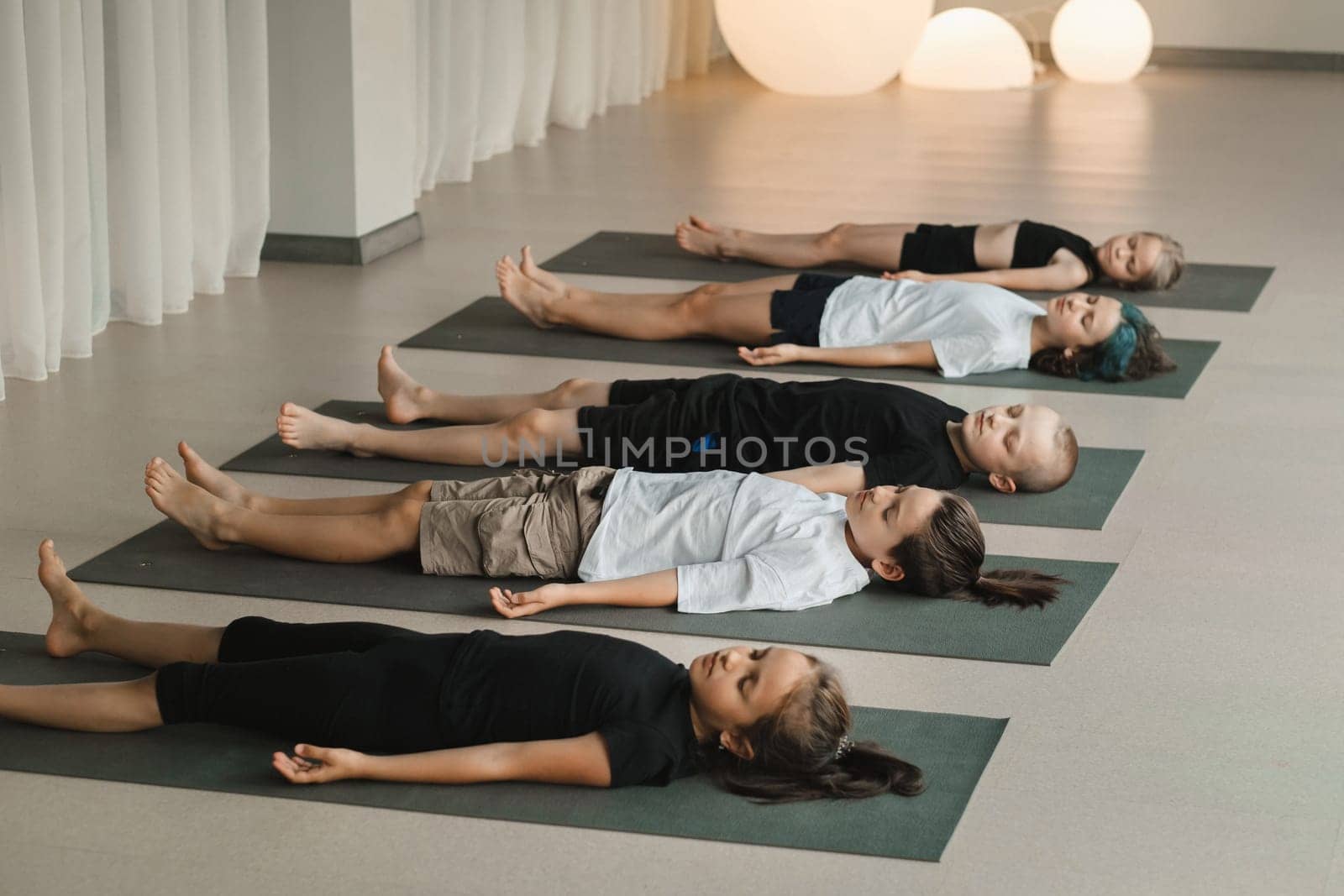 Children lying on the floor relax to the sounds of a Tibetan bowl. Children's yoga.