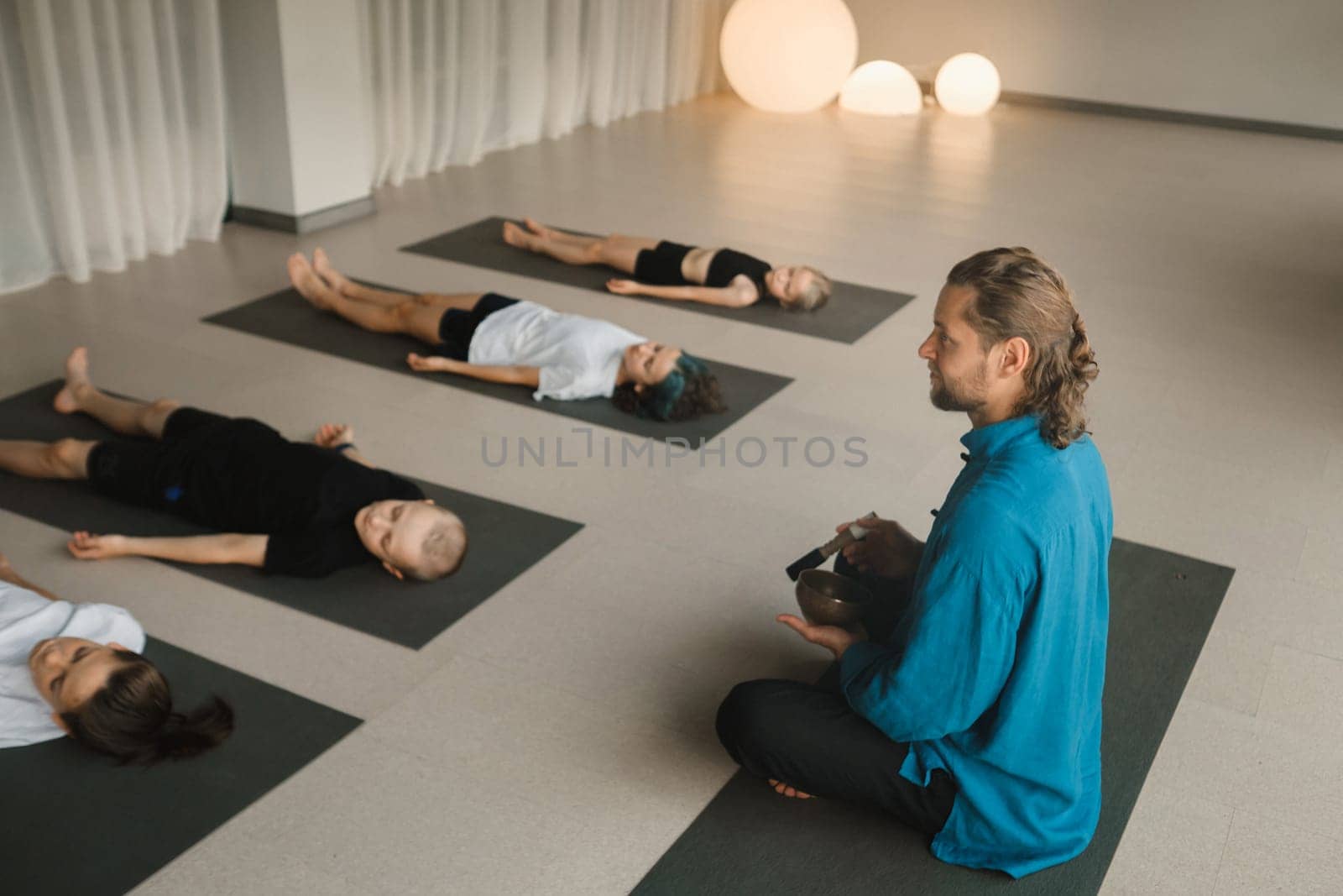 Children relax lying down to the sounds of a Tibetan bowl in the fitness room. Children's yoga by Lobachad