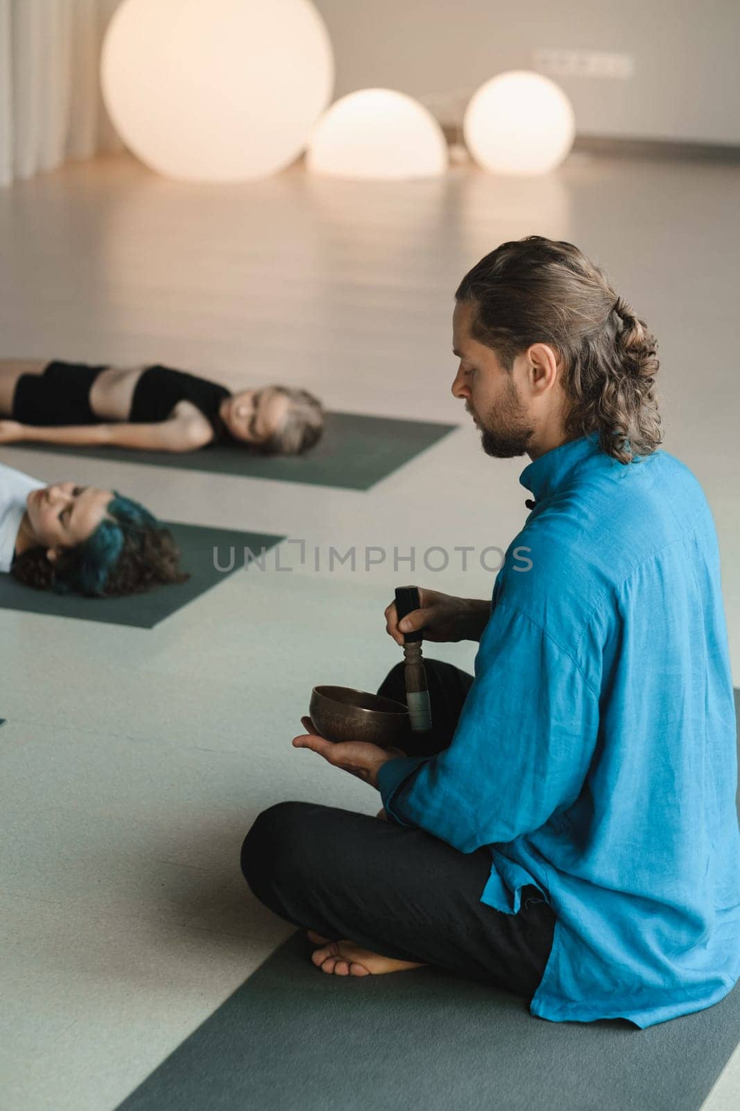 Children relax lying down to the sounds of a Tibetan bowl in the fitness room. Children's yoga.