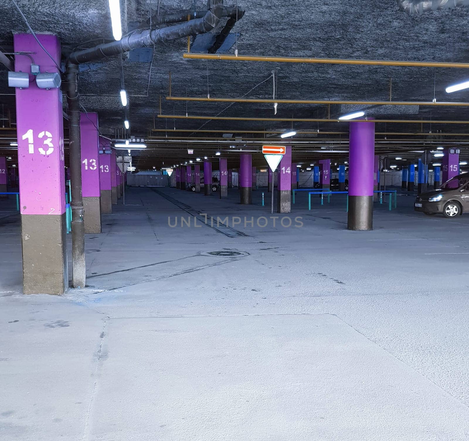 Underground Parking with poles with markings for cars in the shopping center, a place for text at the bottom.