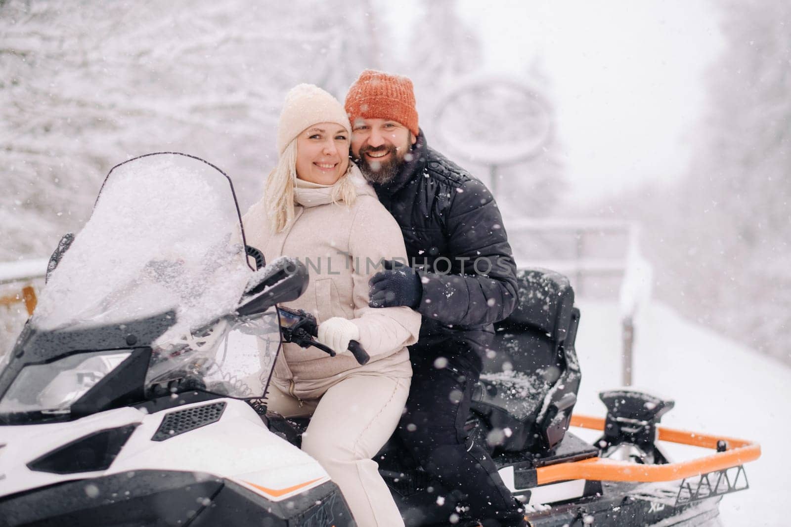 A couple, a man and a woman, on a snowmobile in a winter forest.