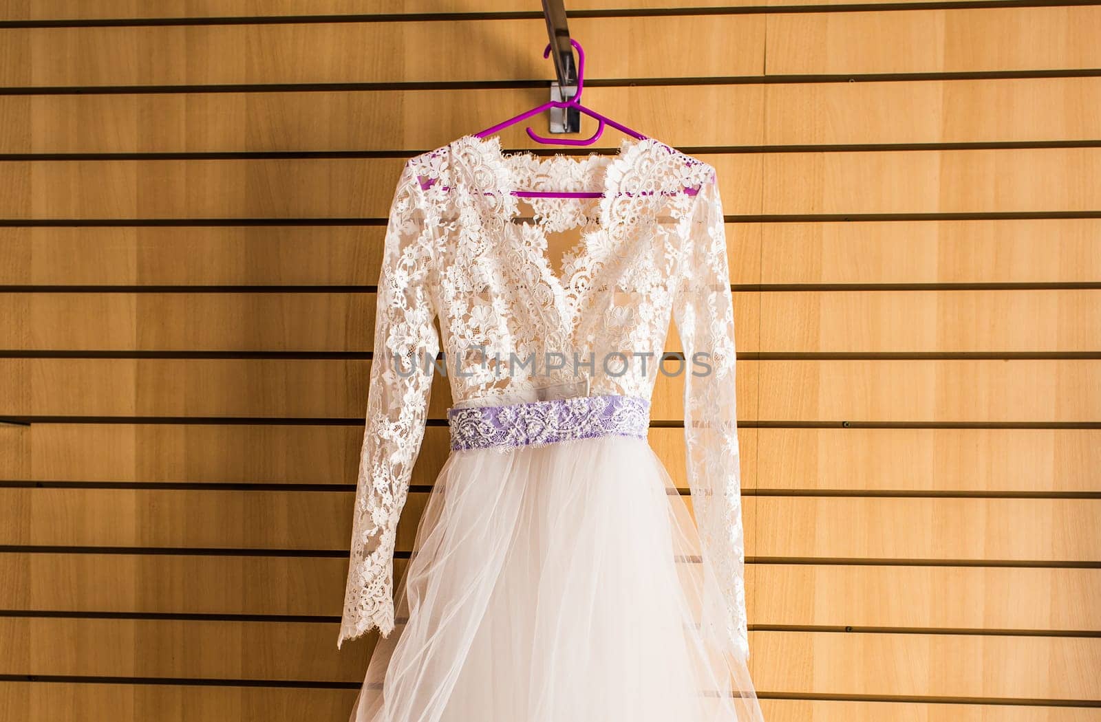 The perfect wedding dress with a full skirt on a hanger in the room of the bride