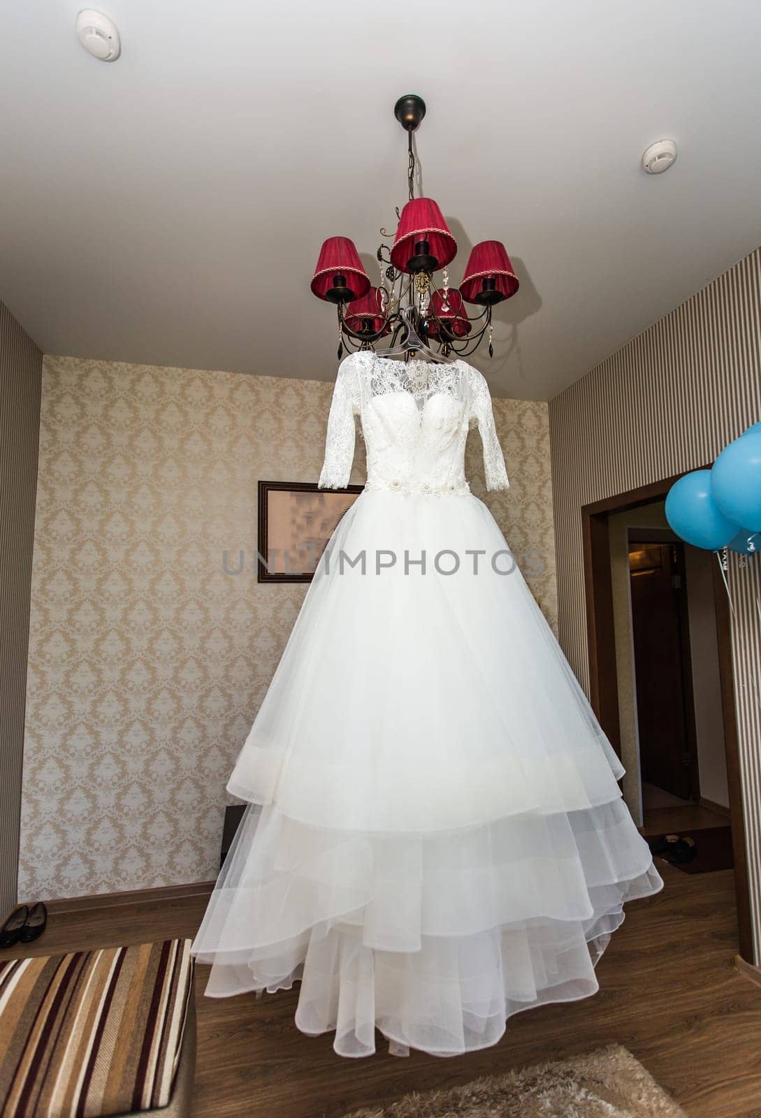 The perfect wedding dress with a full skirt on a hanger in the room of the bride