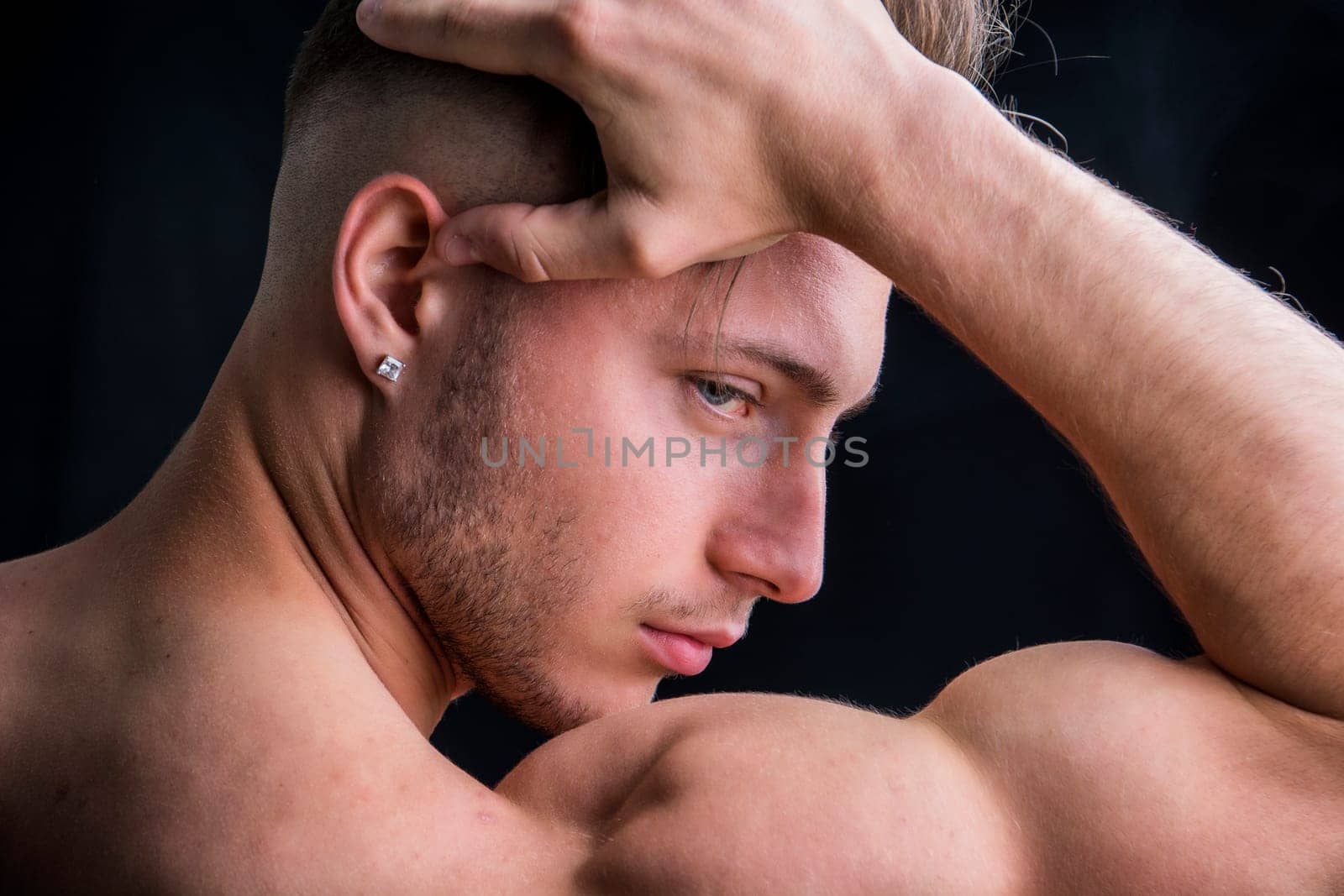 A shirtless man holding his head in his hands