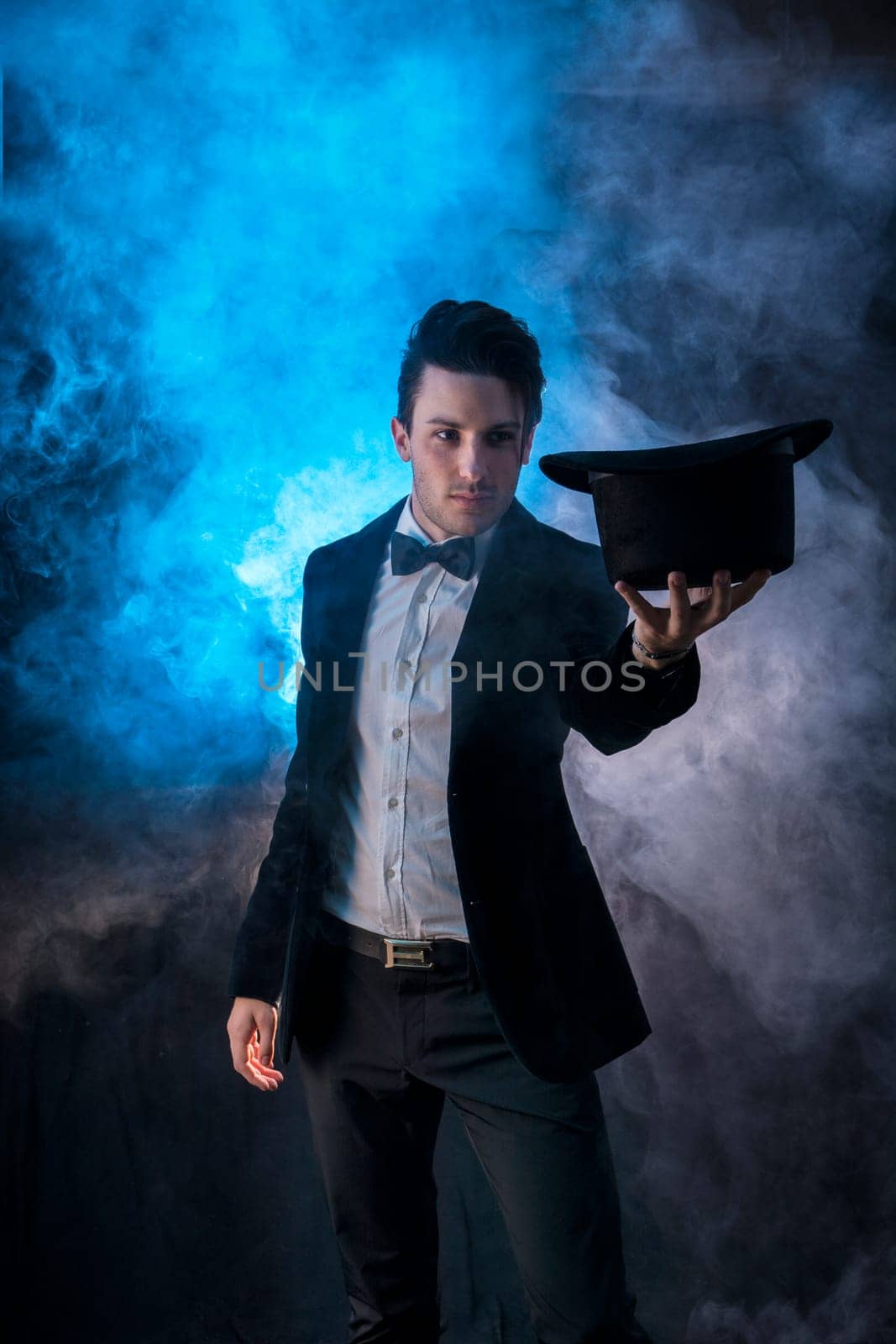 Photo of a stylish man in a tuxedo holding a black hat by artofphoto