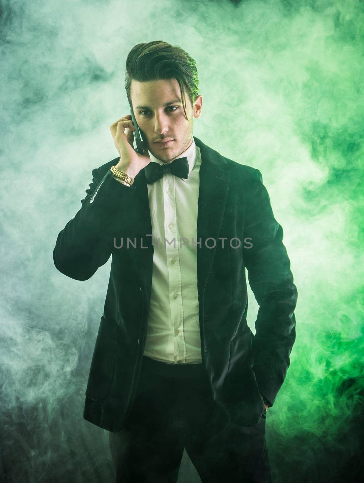A man in a tuxedo talking on a cell phone