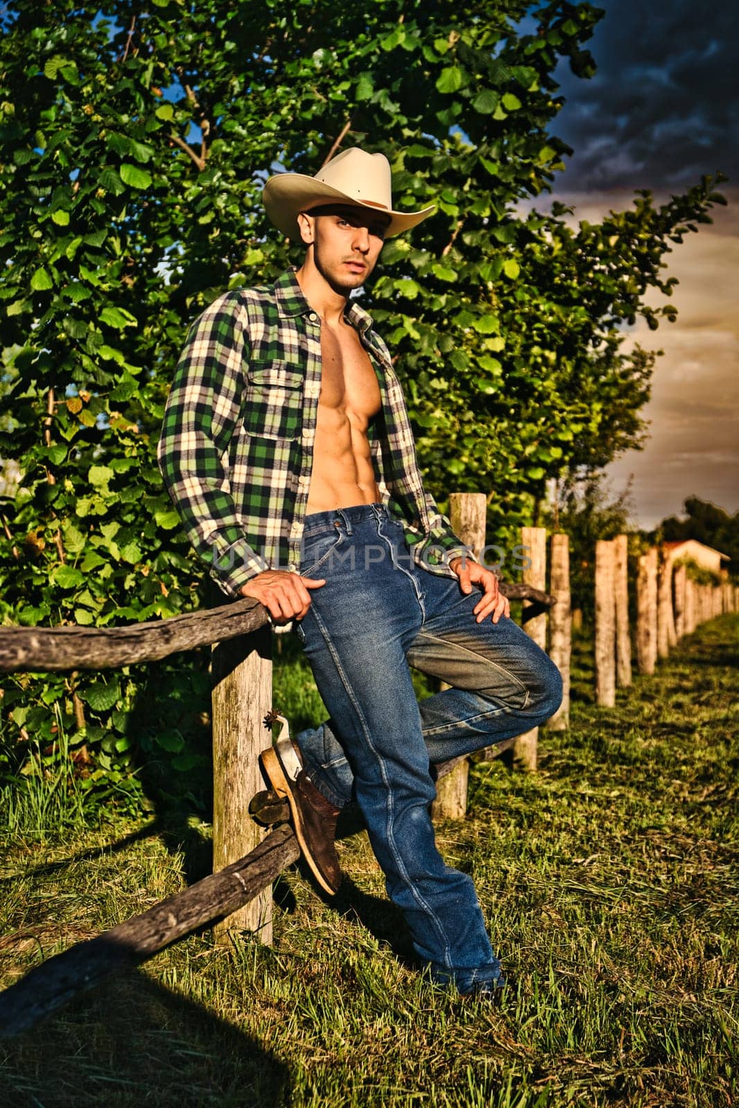 Photo of a shirtless man sitting on a wooden fence by artofphoto