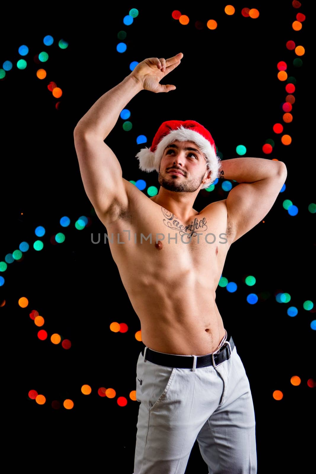 A shirtless man wearing a santa claus hat