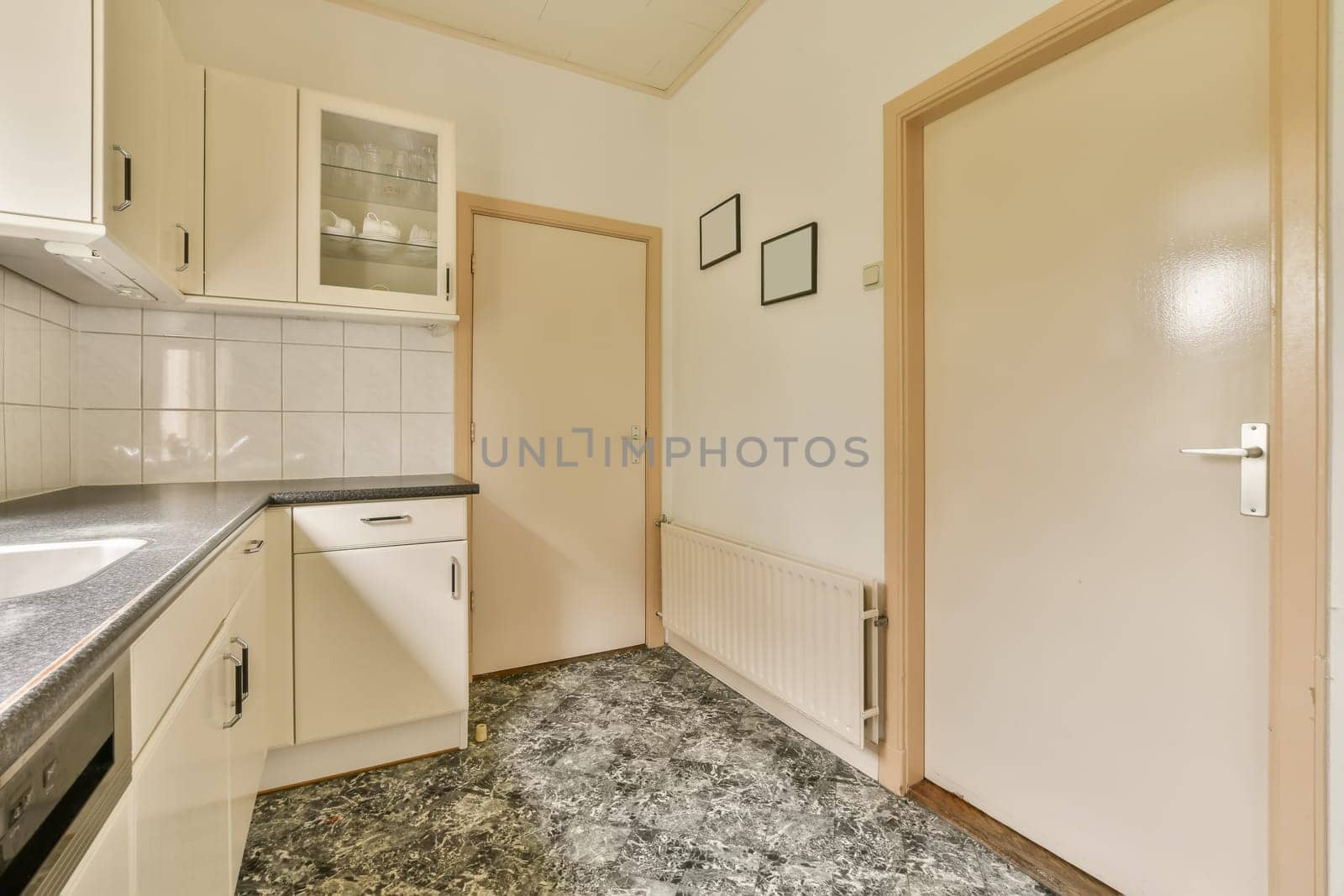 a small kitchen with white cabinets and a door to by casamedia