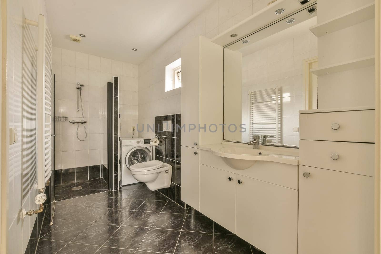a modern bathroom with black and white marble flooring, sink, mirror and shower stall in the corner area