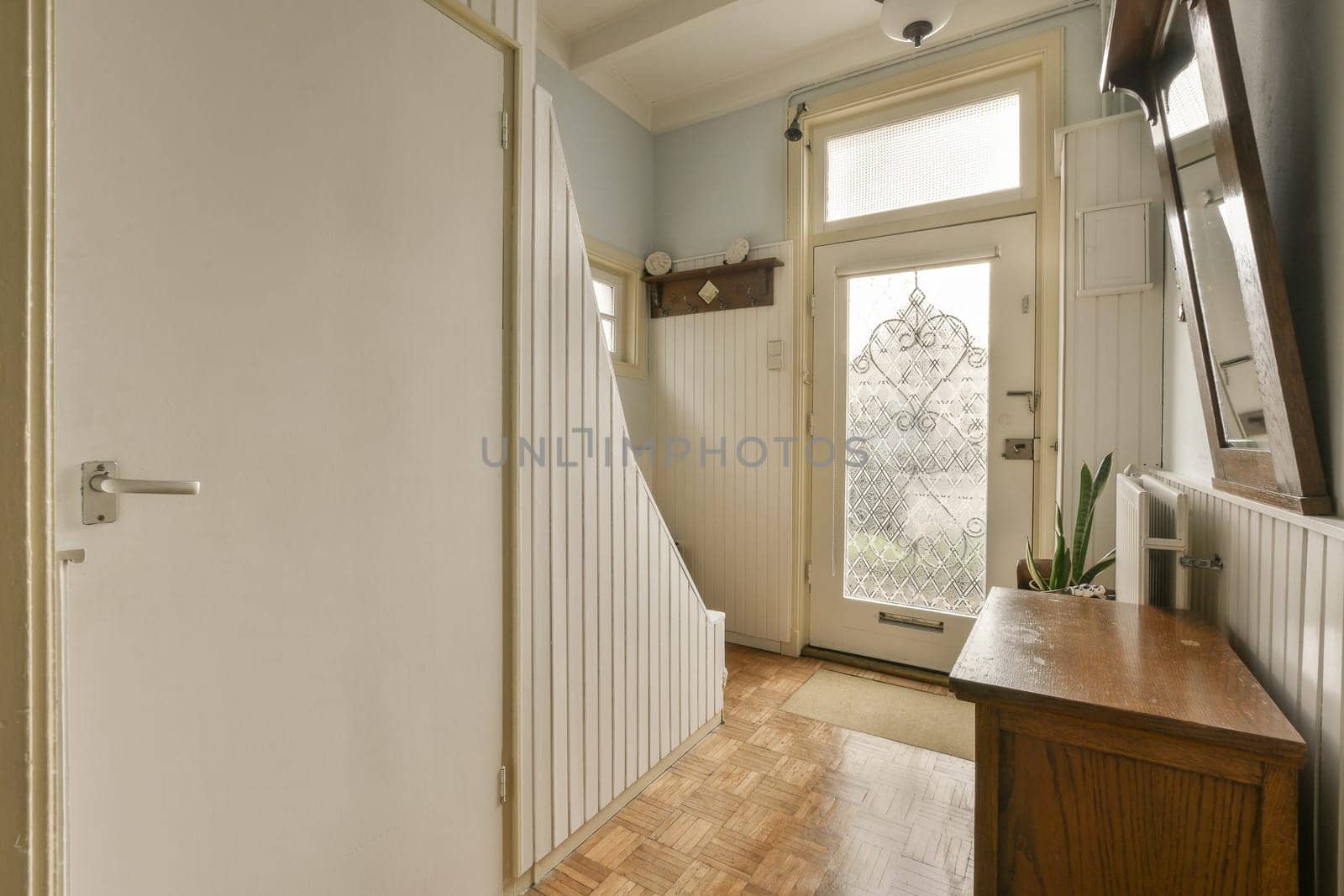 a hallway in a house with wood flooring and white trim on the walls, door is open to another room