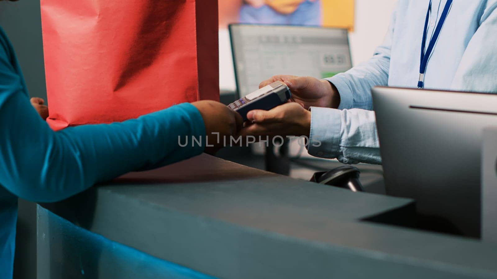 African american client paying for trendy merchandise with credit card using payment terminal during shopping session in modern boutique. Shopaholic woman buying casual wear in clothing store.
