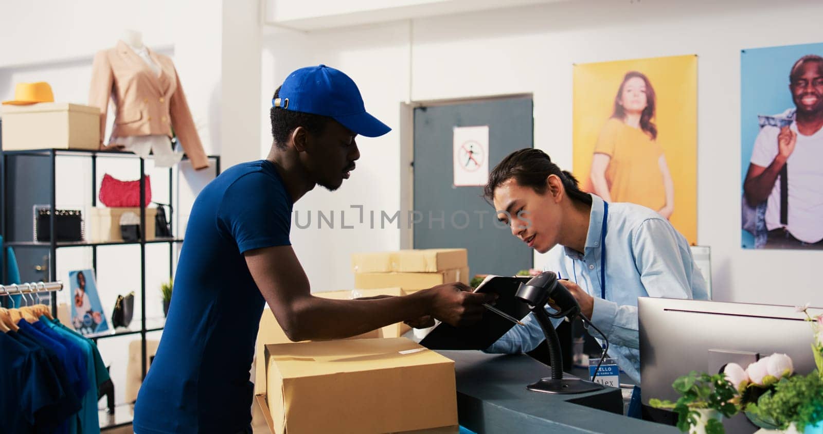 African american deliveryman asking worker to sign delivery report, discussing clients shipping detalis in shopping centre. Courier taking cardboard boxes, preparing to ship packages to customers