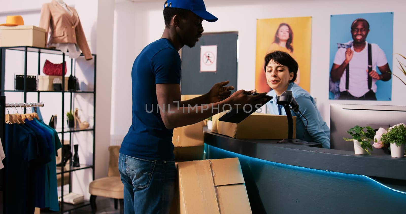 African american store courier discussing packages distribution with manager, showing shipping report in modern boutique. Stylish employee working at online orders, preparing boxes for delivery