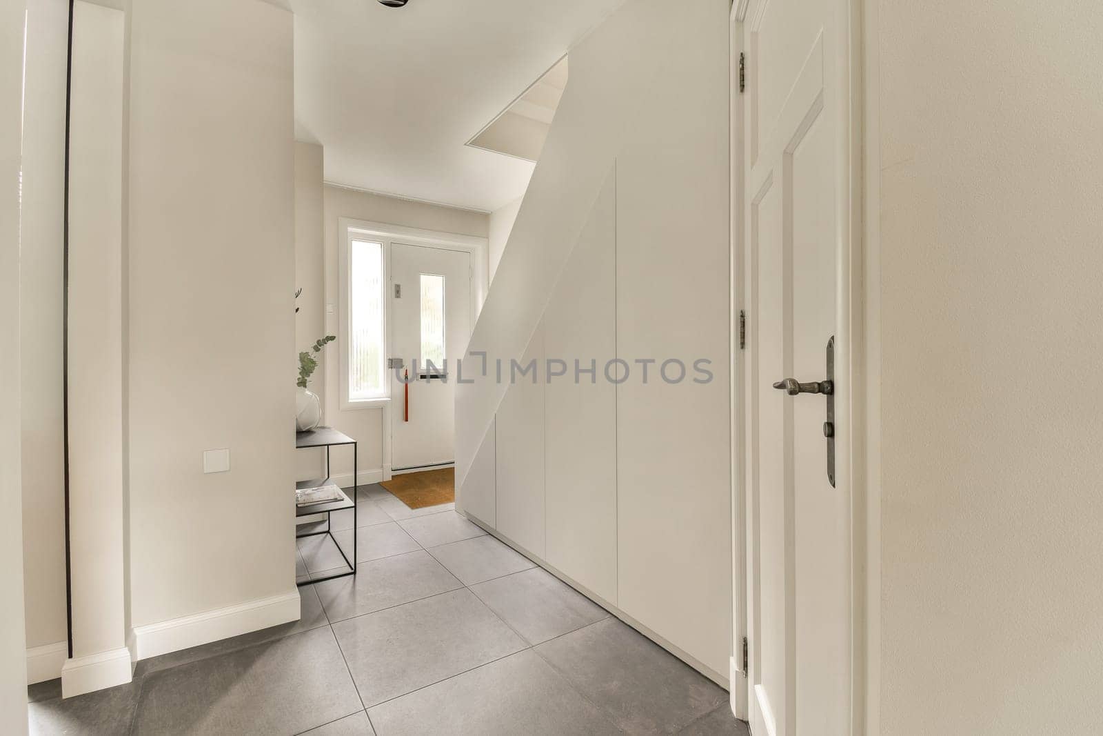 a white hallway with a white door and a staircase by casamedia