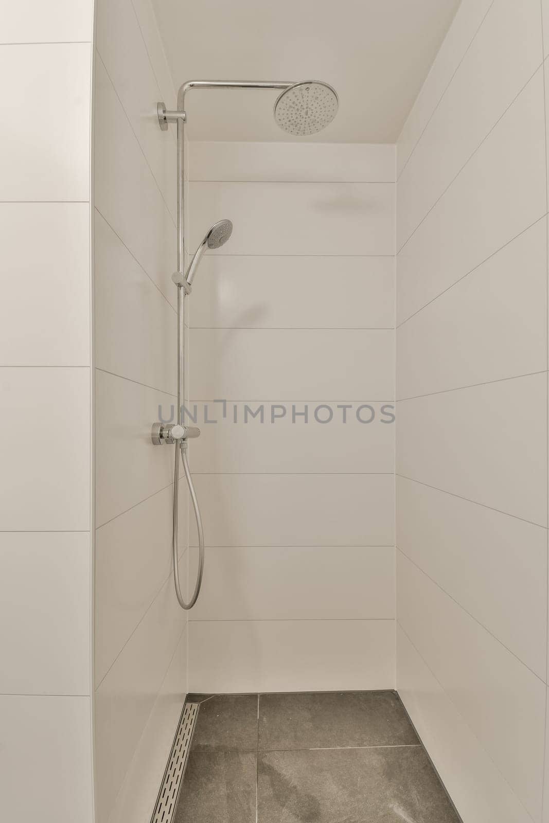 a walk in shower with tile flooring and white tiles on the wall behind it is an open shower head