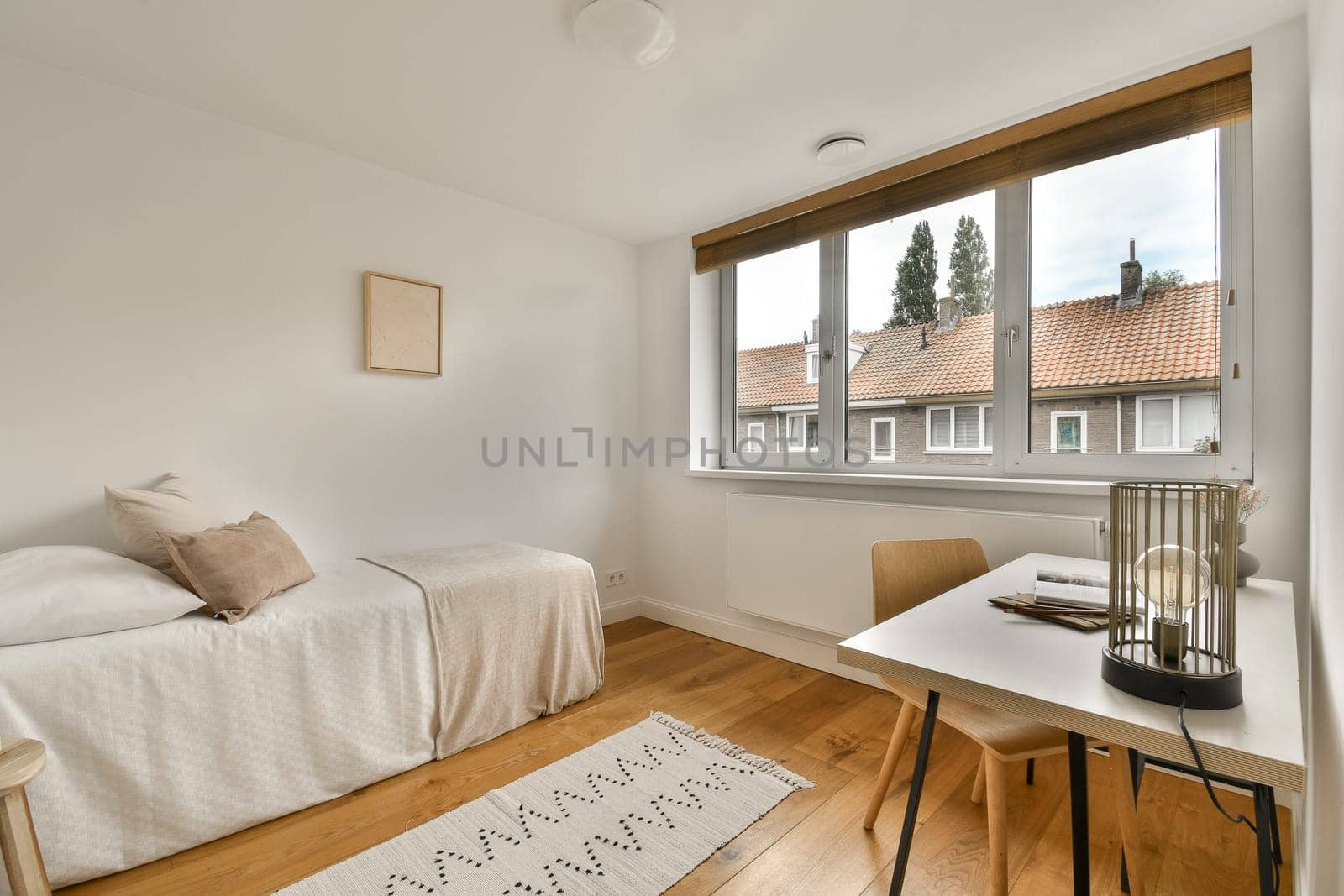 a bedroom with a bed, desk and window looking out onto the street in front of the apartment's windows