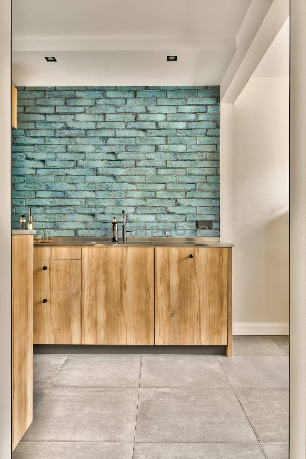 a kitchen with wood cabinets and a blue brick wall by casamedia