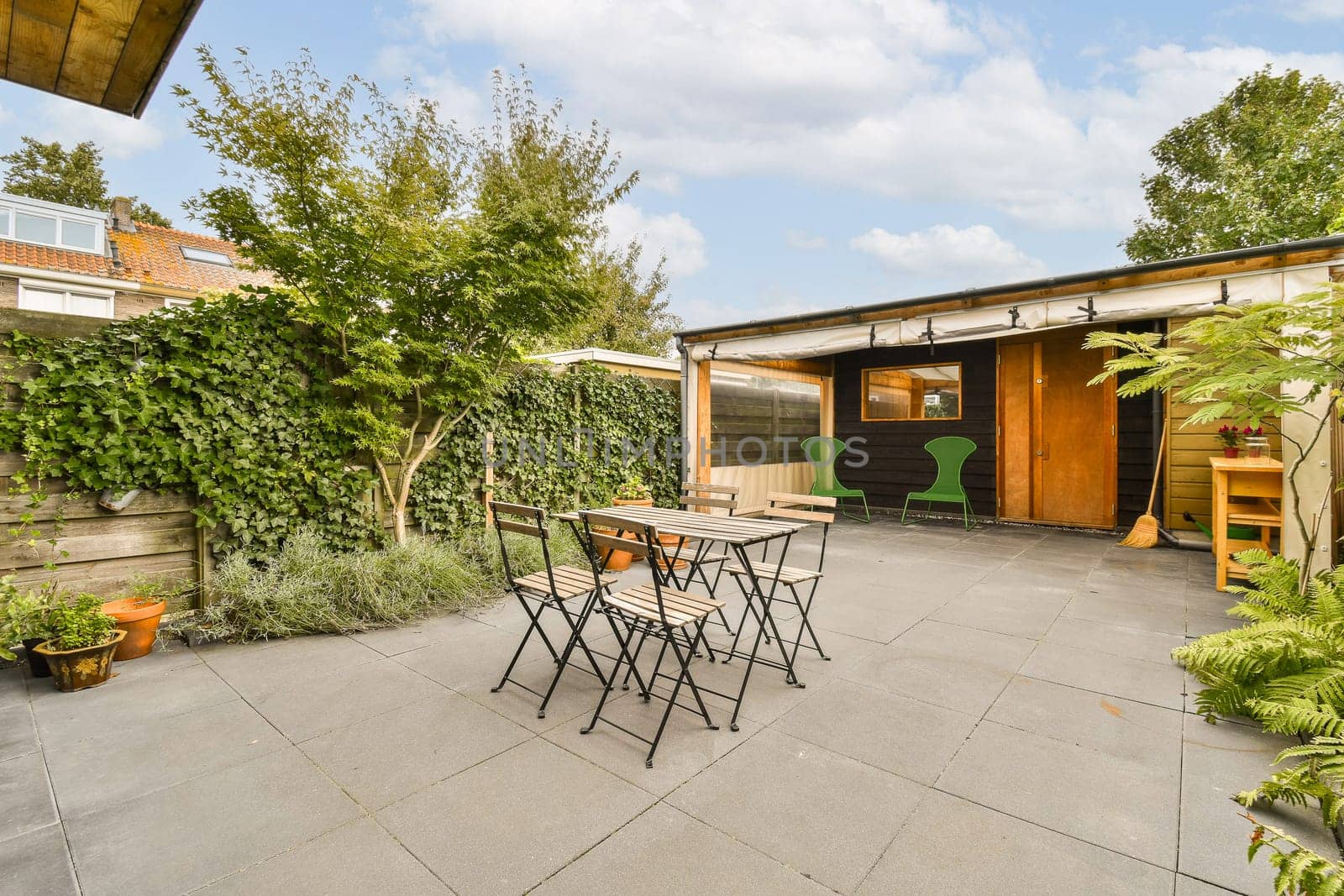 a patio with a table and chairs and a shed by casamedia