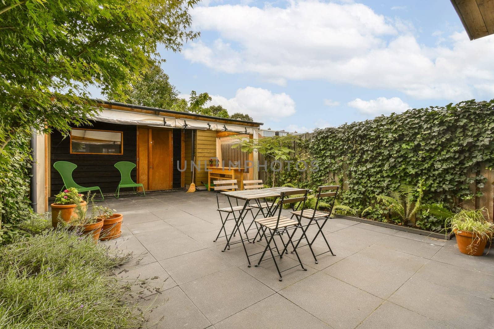 a patio with a table and chairs and a shed by casamedia