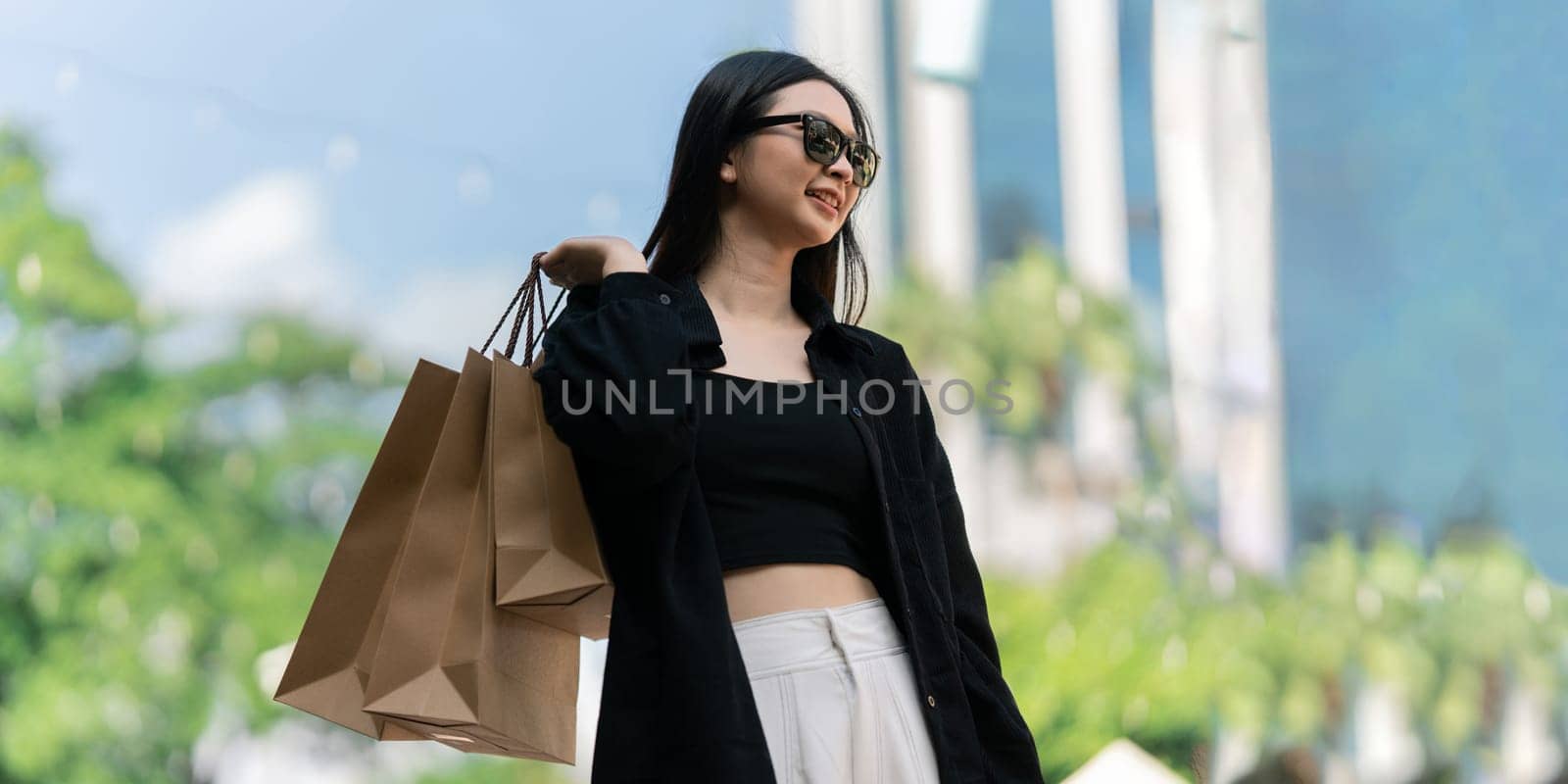 Young asian woman in shopping. Fashion woman in black with shopping bag walking out store after shopping. Black friday.