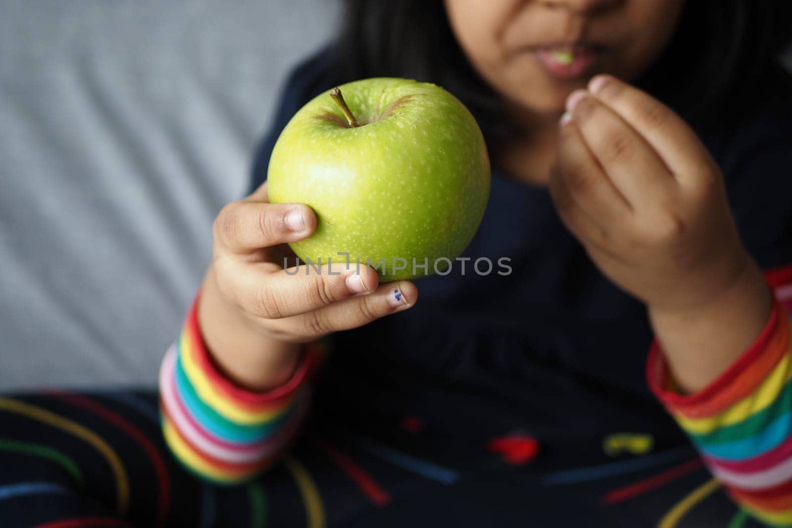 child bitting a green apple close up .