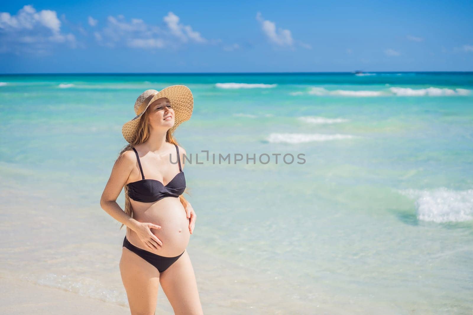 Radiant and expecting, a pregnant woman stands on a pristine snow-white tropical beach, celebrating the miracle of life against a backdrop of natural beauty by galitskaya